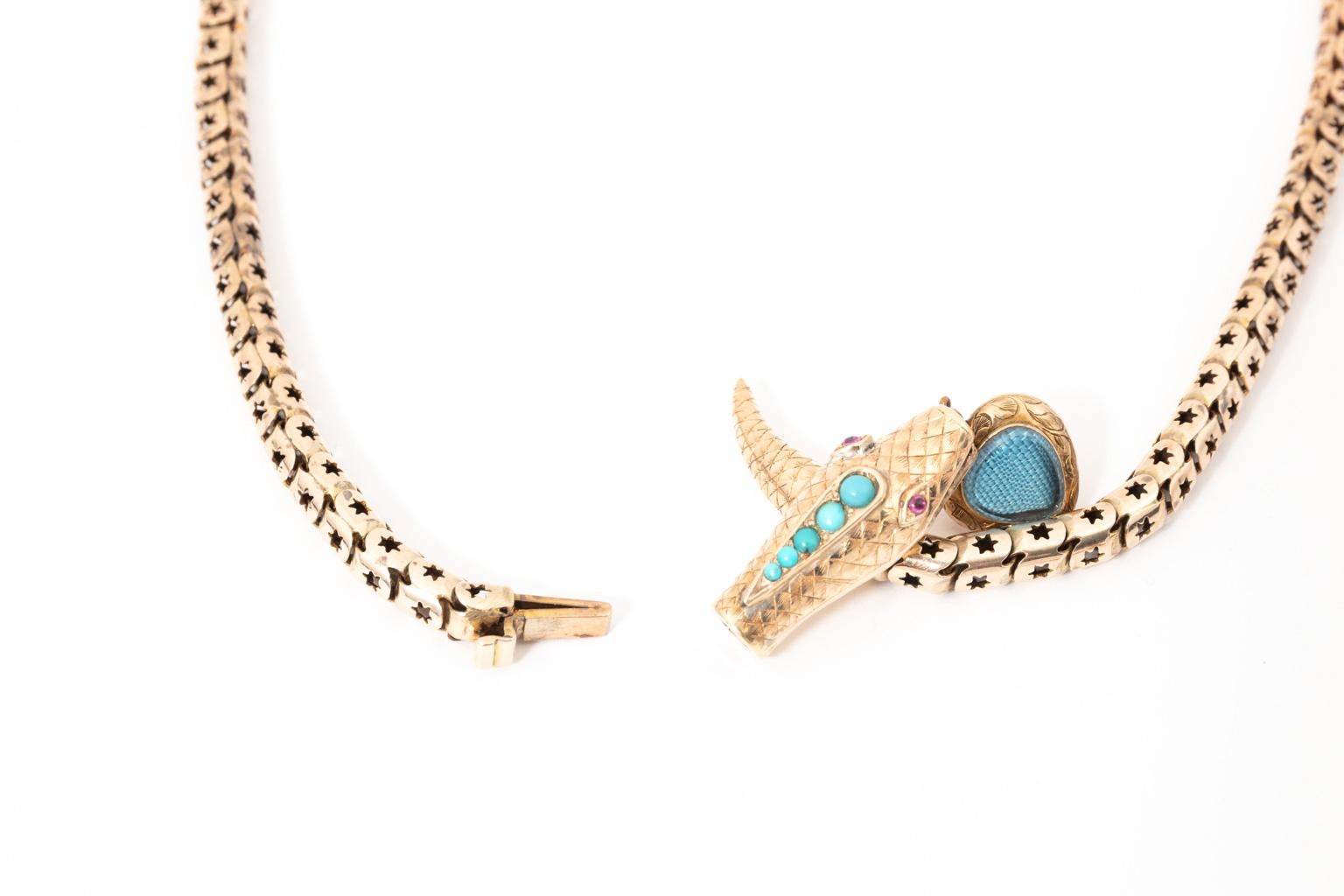 Circa 1850s early Victorian serpent necklace with snake's head in 24 Karat Gold, embellished with fine Turquoise stones and Ruby eyes. It also features a decorative heart suspended from its mouth which also includes Turquoise stones. Weight 30.70