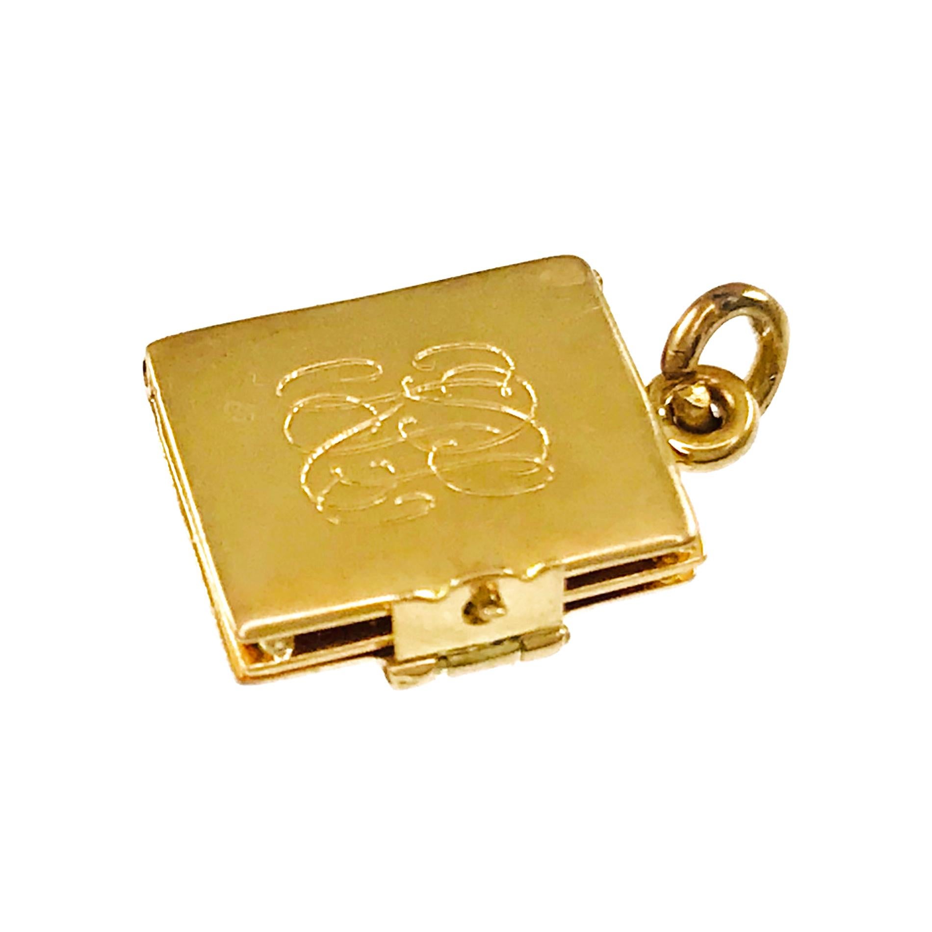 14 Karat Hinged Mini Booklet Pendant. The pendant has an overall smooth shiny finish and three pages/panels with a hinged closure. The front and back cover is monogrammed with script letters. On the inside cover in all capitals are the words FROM