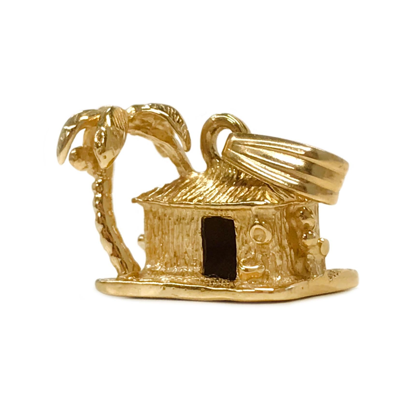 Absolutely adorable 14 Karat Yellow Gold Island Hut with Palm Tree Pendant. The pendant has texture on the hut and palm tree and measures 10.5mm tall x 14.6mm wide. Stamped on the bottom is the maker's mark (Crown with an S inside) and 14K. This