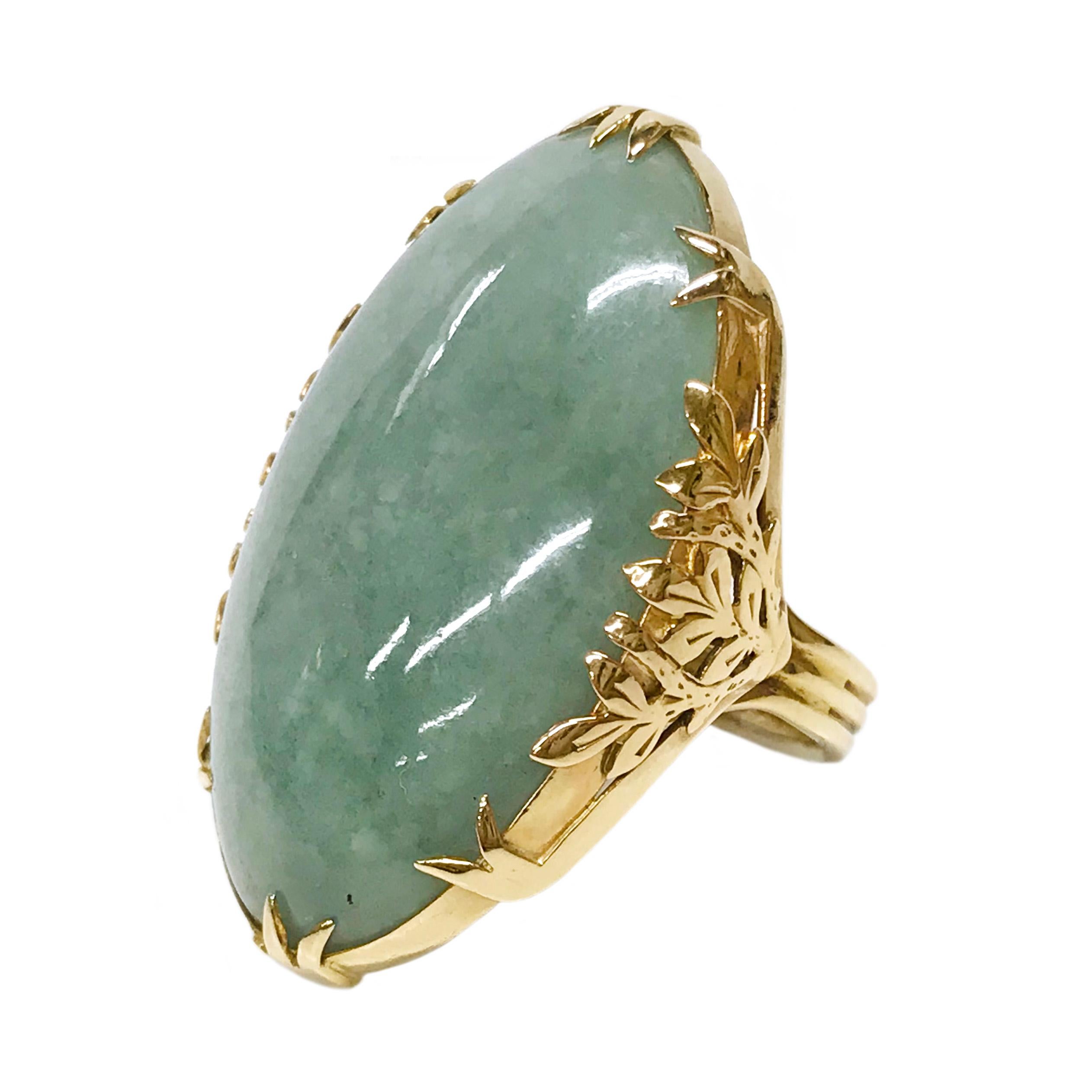 14 Karat Jadeite Navette Ring. The ring features a large jadeite cabochon measuring 36.9 tall x 23.2mm wide. There is a thin band under the gallery which combines with two other thin bands creating one larger band. The prongs are leaf-like in shape