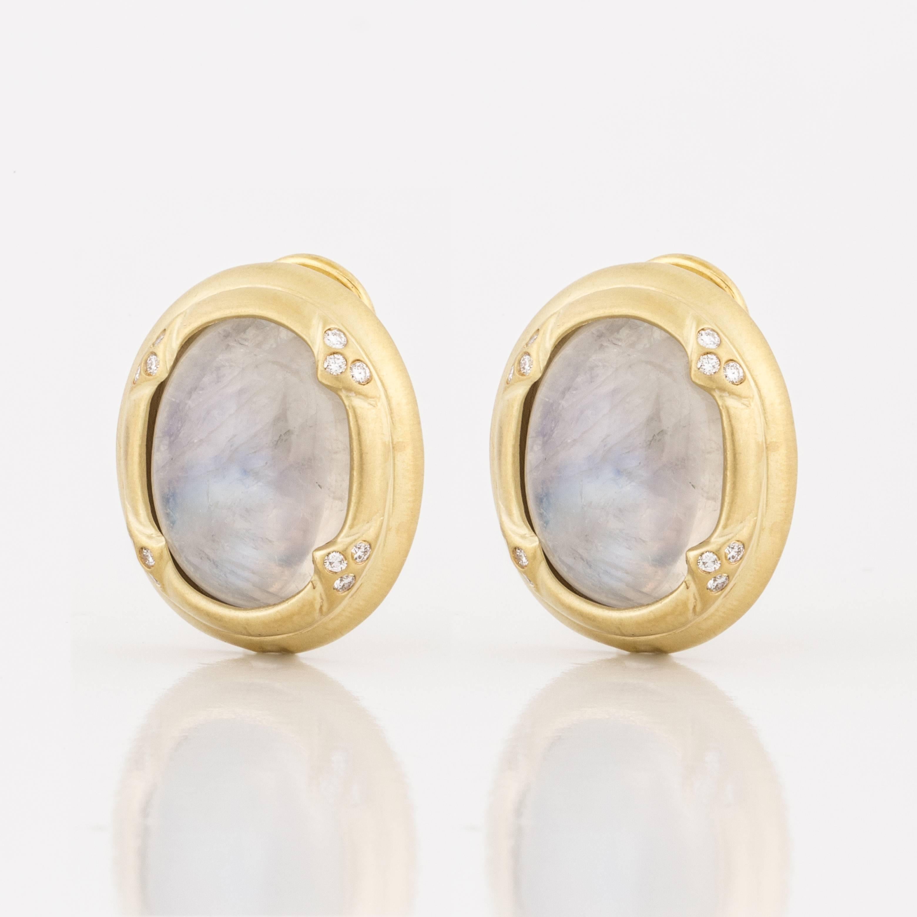 Mazza button style earring crafted in 14K yellow gold featuring oval cabochon moonstones, accented by round diamonds.  There are 24 round brilliant-cut diamonds that total 0.25 carats; F-G color and VS1-2 clarity.  The gold has a soft brushed
