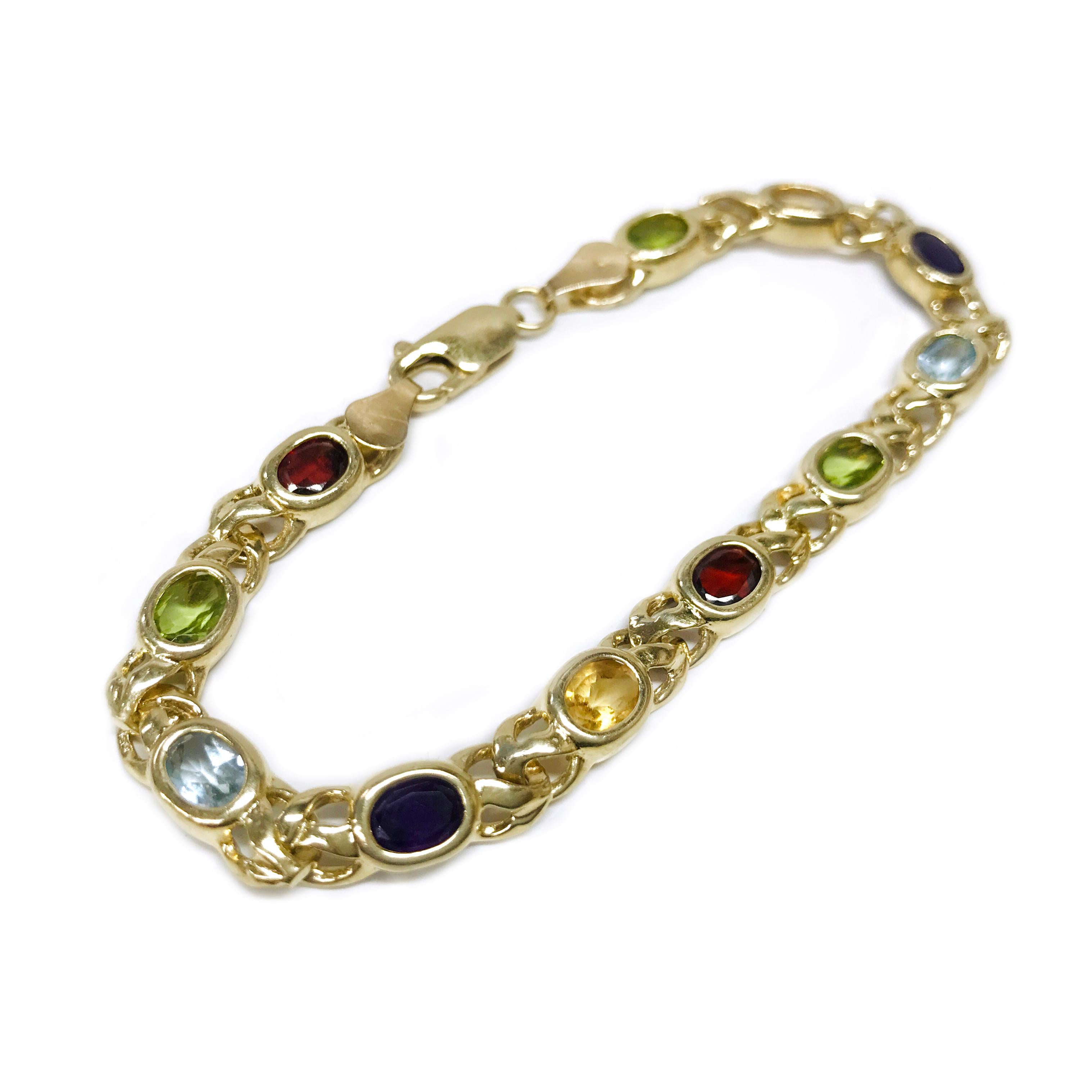 14 Karat Multi-Gemstone bracelet. This colorful link bracelet contains eleven oval faceted gemstones bezel-set in yellow gold, the bezel is approximately 6 x 4mm. The bracelet includes two garnets, two citrines, two amethyst, two aquamarines, and