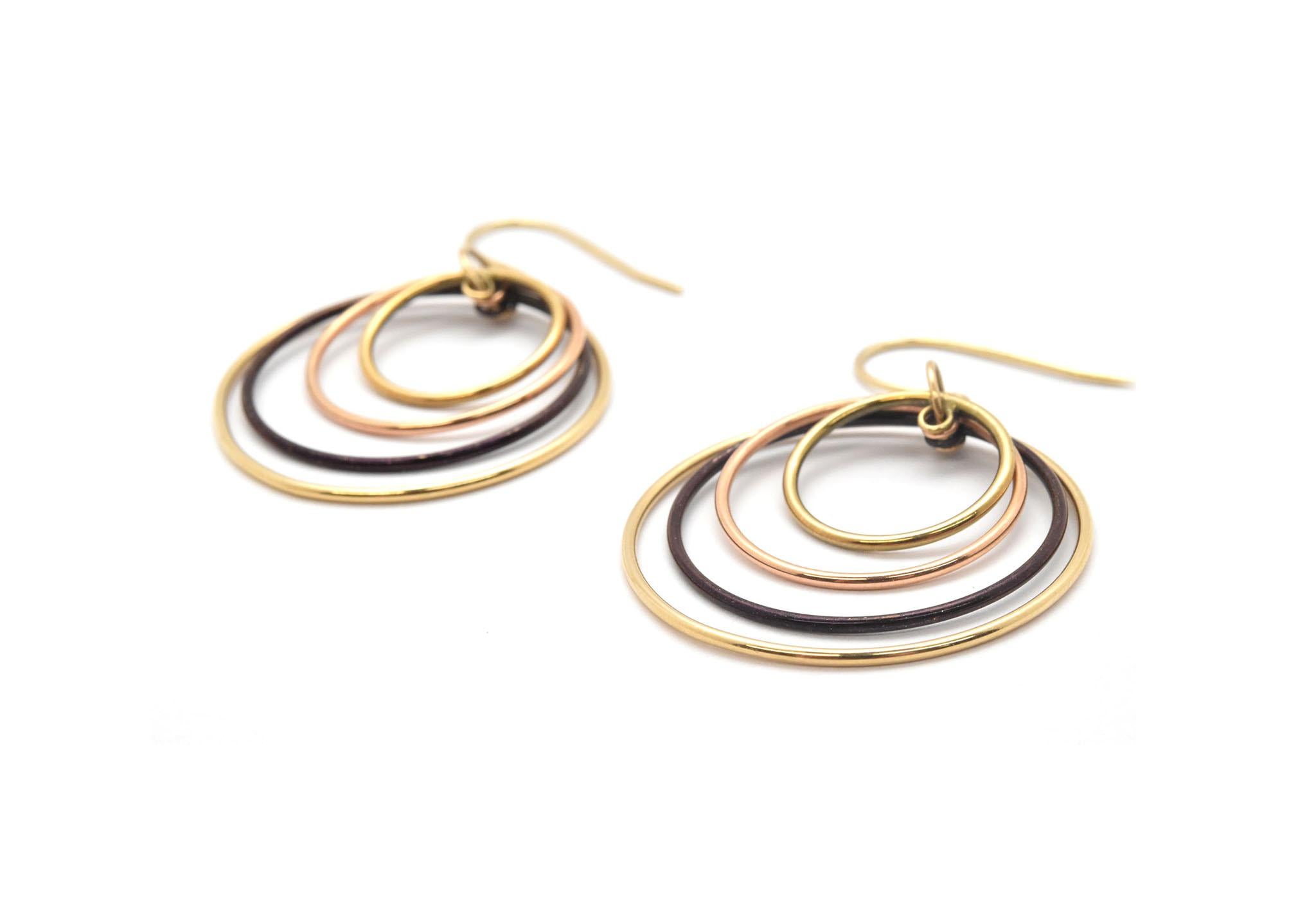 This unique dangle style earrings are designed in 14k yellow gold, rose gold and black rhodium. Dangling from the fish hook backs, there is a loop holding all of the dangling circles. Each circle differs in size, the smallest circle is round and