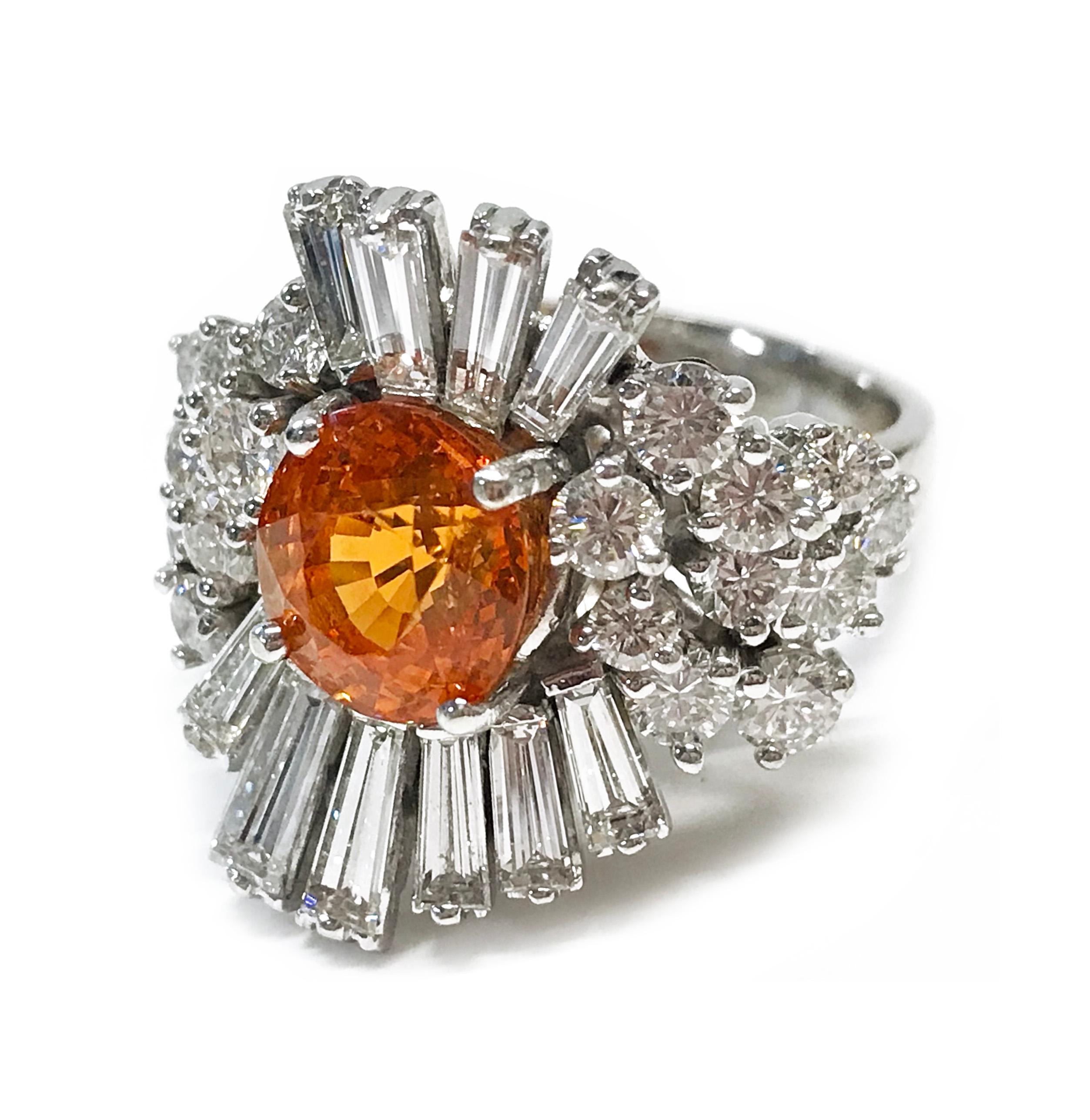 14 Karat Orange Garnet Diamond Cocktail Ring. The ring features a center round orange Spessartite Garnet with ten round brilliant-cut diamonds on either side and ten baguette diamonds on the top and bottom total. The total carat weight of the 8.5mm