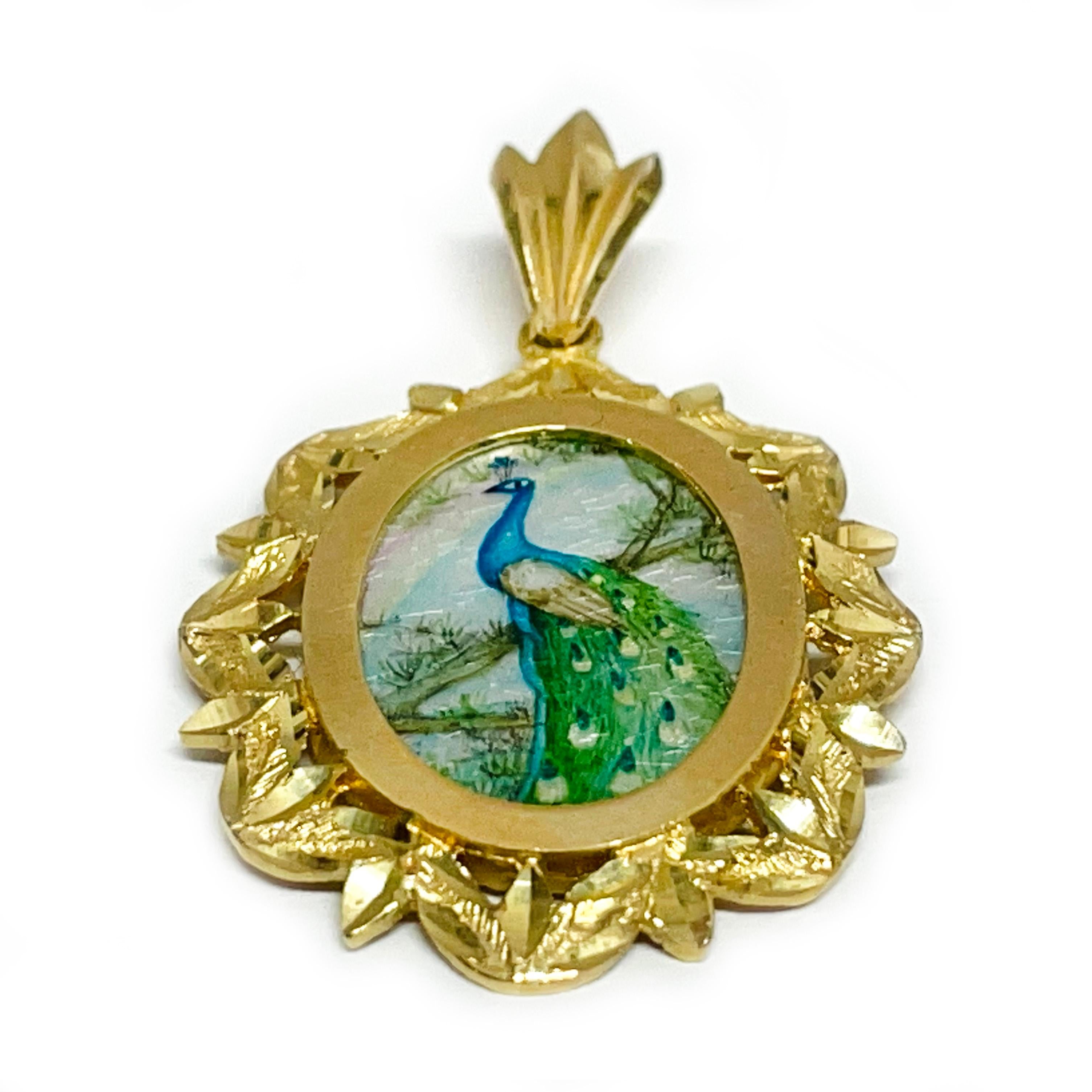 14 Karat Yellow Gold Peacock Hand Painted on a Mother of Pearl Pendant. The miniature painting is set in a 14 karat gold ornate oval frame with diamond-cut details. The painting is signed by the master artist, Luo-Afi-Ping and includes a