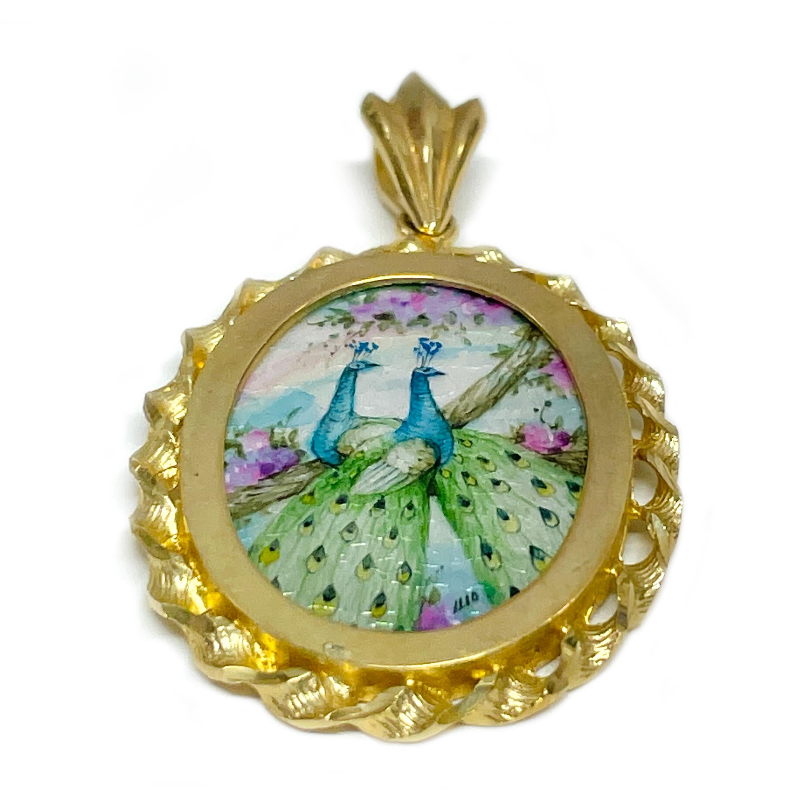 14 Karat Yellow Gold Peacocks Hand Painted on a Mother of Pearl Pendant. The miniature painting is set in a 14 karat gold twisted rope oval frame with diamond-cut details. The painting is signed by the master artist, Luo-Afi-Ping and includes a
