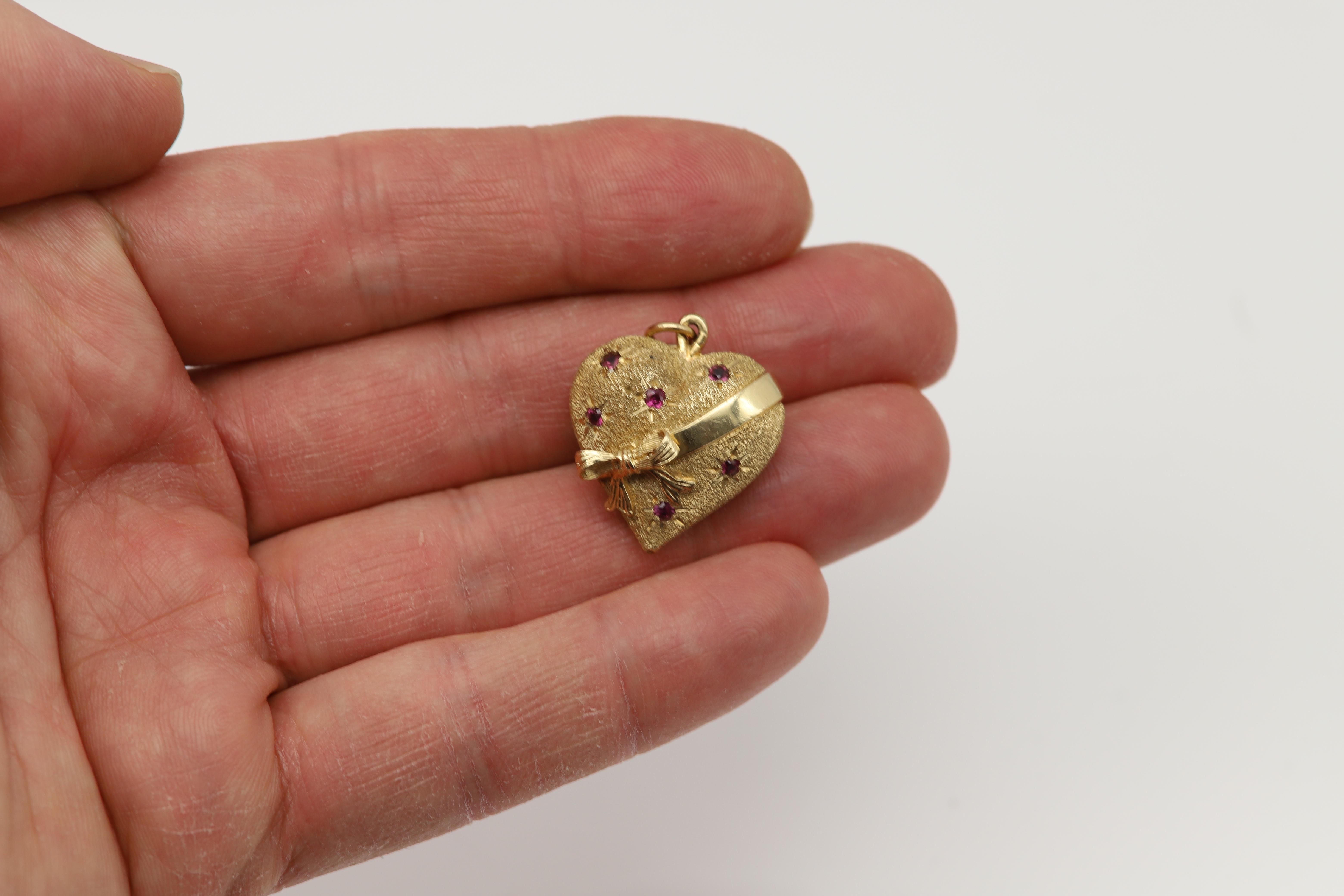 Ciondolo a cuore gonfio vintage 
Design con papillon e pietre di rubino
la maggior parte della superficie è di tipo sabbiato, non è lucidata.
Oro giallo 14k circa 8,8 grammi
Circa 1950, usato - Buone condizioni
Dimensioni: 1' pollici 
Rubino