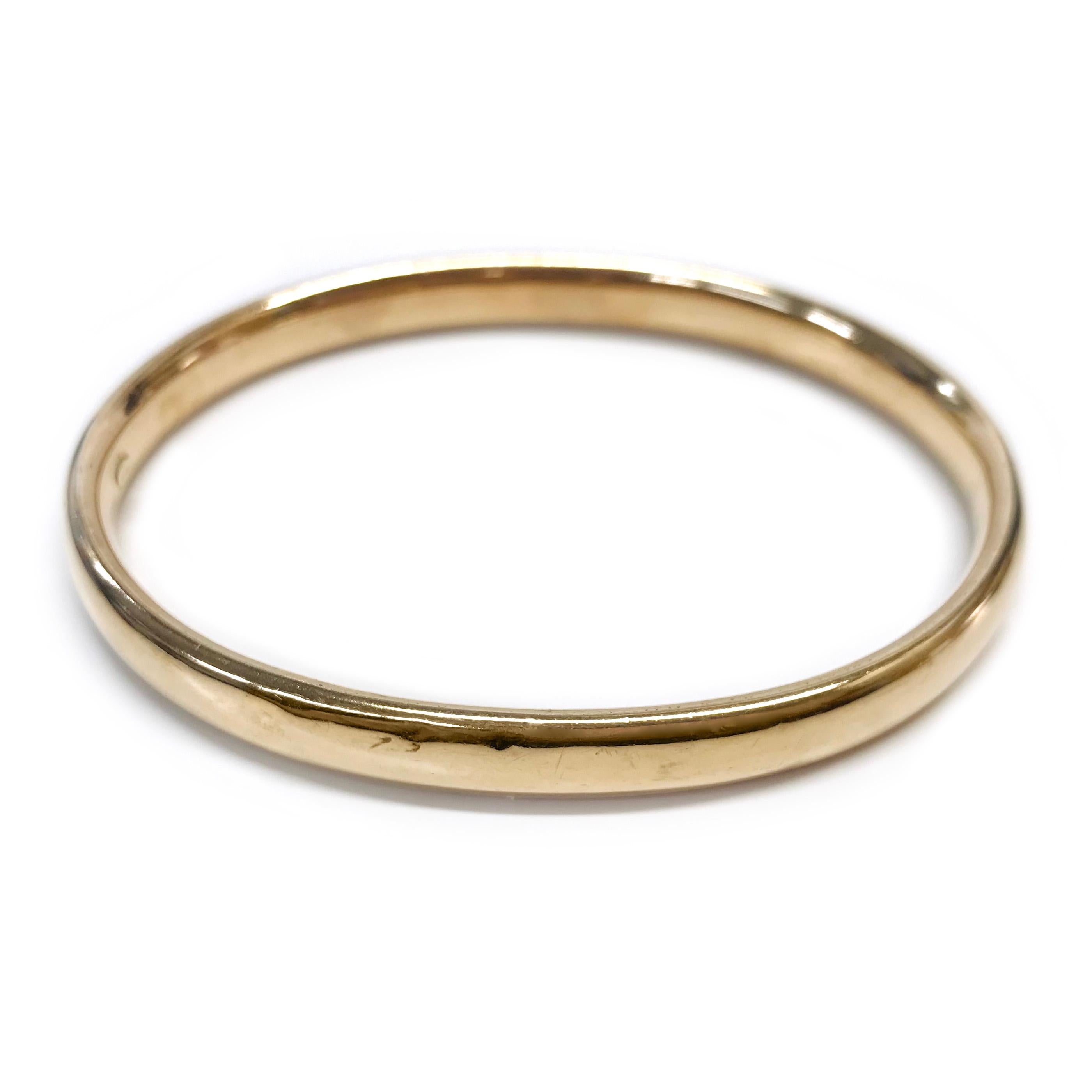 14 Karat Rose Gold Bangle Bracelet. The bangle has an all-around smooth shiny finish. There are approximately ten small dents on the outer surface of the bangle. The bangle measures 7.0mm wide x 4.0mm deep. There is a raised circular maker's mark on