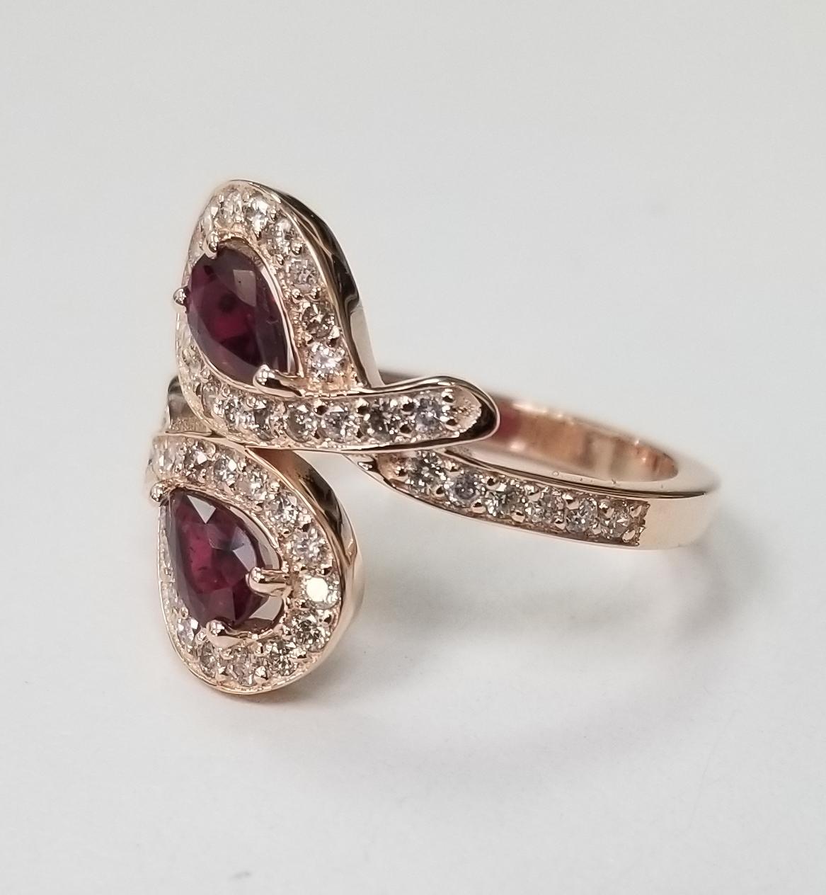 Rubin- und Diamantring aus 14 Karat Roségold, mit 2 birnenförmigen Rubinen in Edelsteinqualität mit einem Gewicht von 0,90 Pence und 48 runden Diamanten im Vollschliff von sehr guter Qualität mit einem Gewicht von 0,55 Pence.  Dieser Ring ist eine