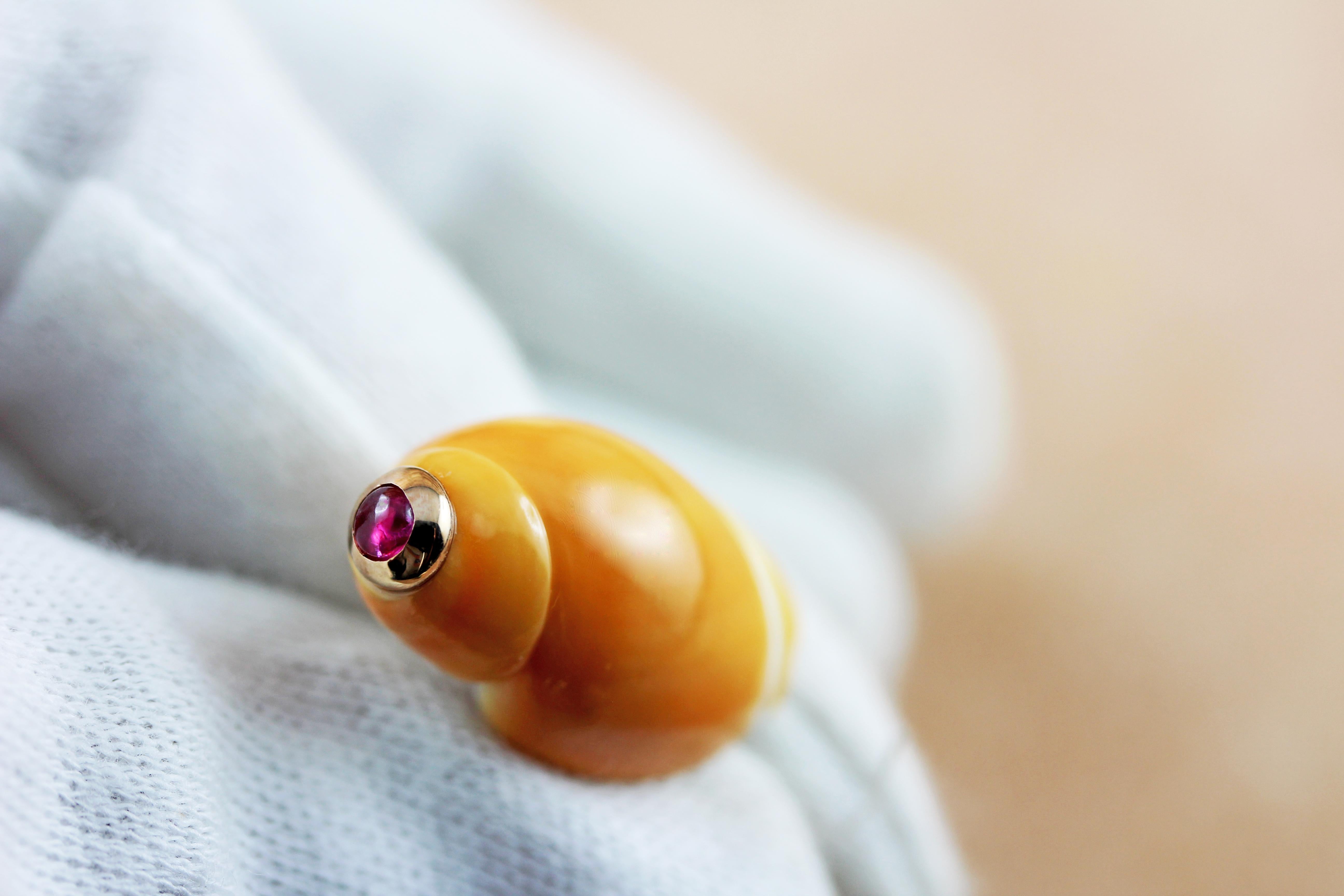The striking orange shade and natural texture of this shell, adorned with a cabochon ruby, is the protagonist of the front face of this elegant pair of cufflinks, which also features the same shell but smaller like a toggle.

 All AVGVSTA jewelry is