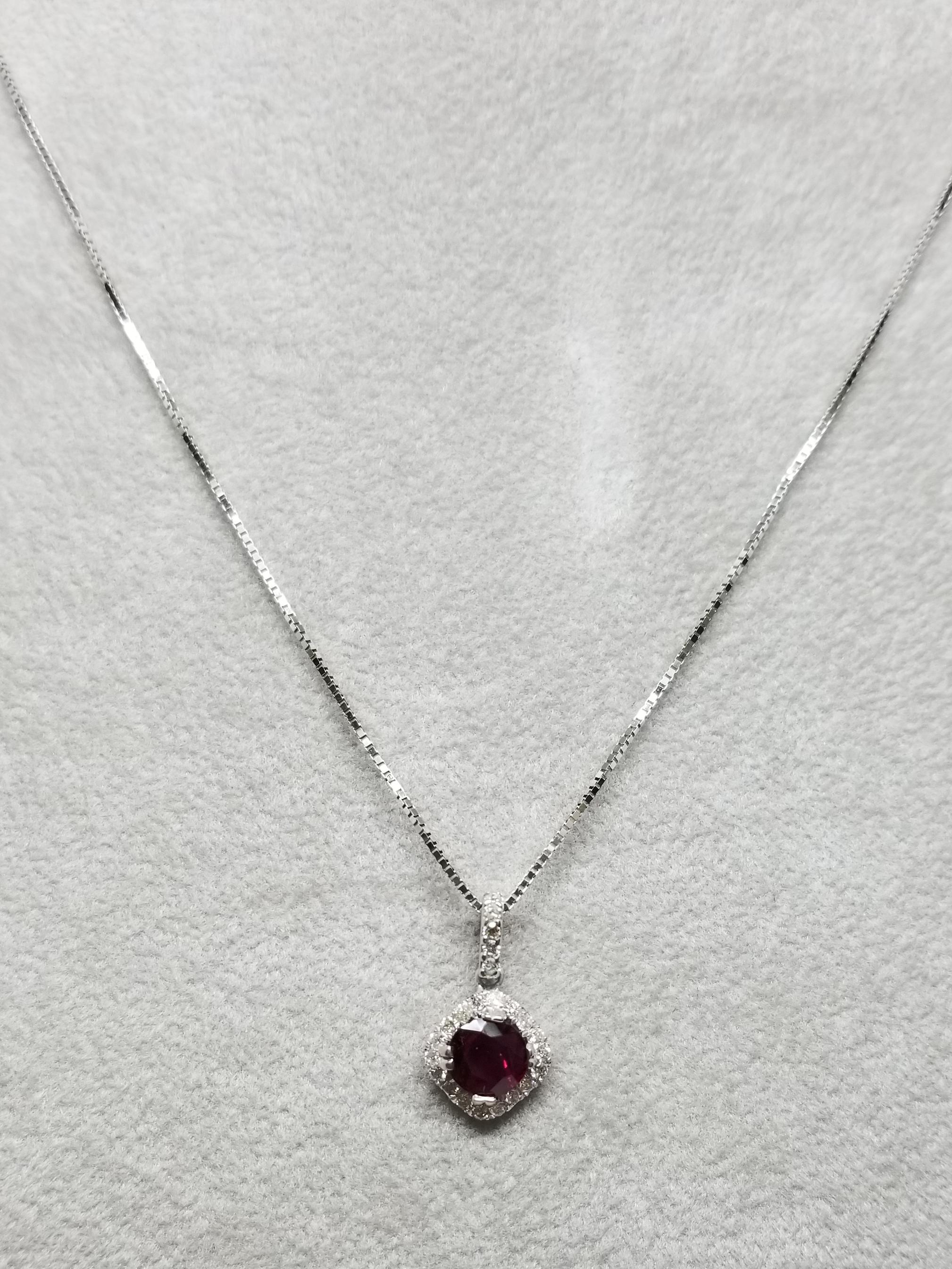 14 karat Ruby and diamond halo pendant, containing 1 round ruby of gem quality weighing .90cts. and 26 round full cut diamonds of very fine quality weighing .25pts.