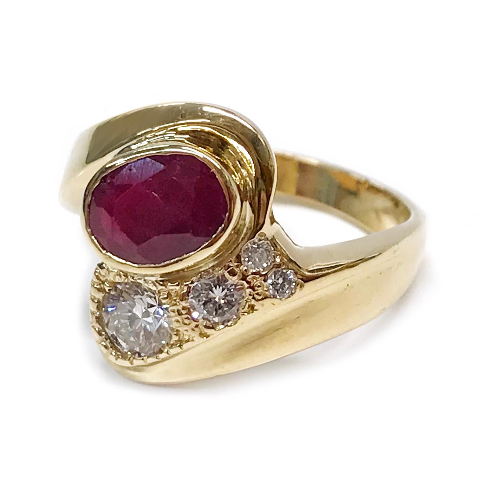 14 Karat Ruby Diamond Ring. The ring features a 7.8 x 6.8 x 3mm bezel-set oval Ruby, and four flush-set round diamonds set into two intersecting gold swooshes. The ruby has a carat weight of 1.39ct. The diamonds have a total weight of 0.47ctw. The
