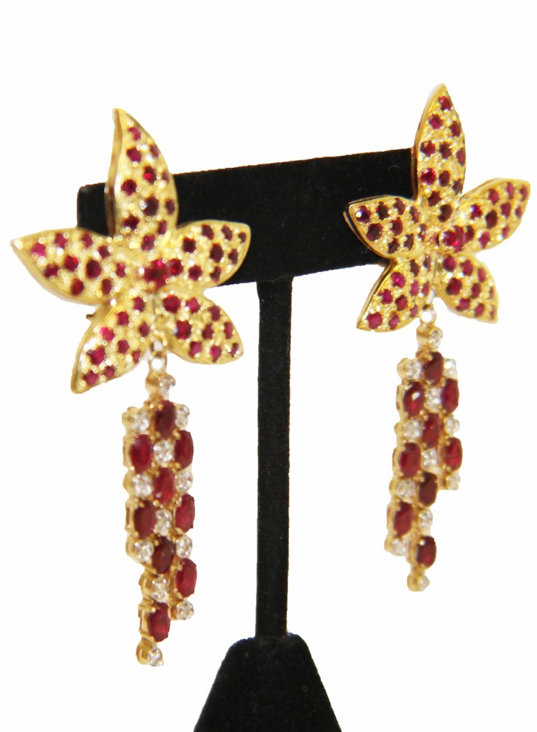 14 karat yellow gold meticulously crafted into 5 graceful petals encrusted with beautifully matched, round faceted rubies create a flower of uncompromising beauty!  Removable enhancers seductively dangle and effortlessly provide day-to-evening