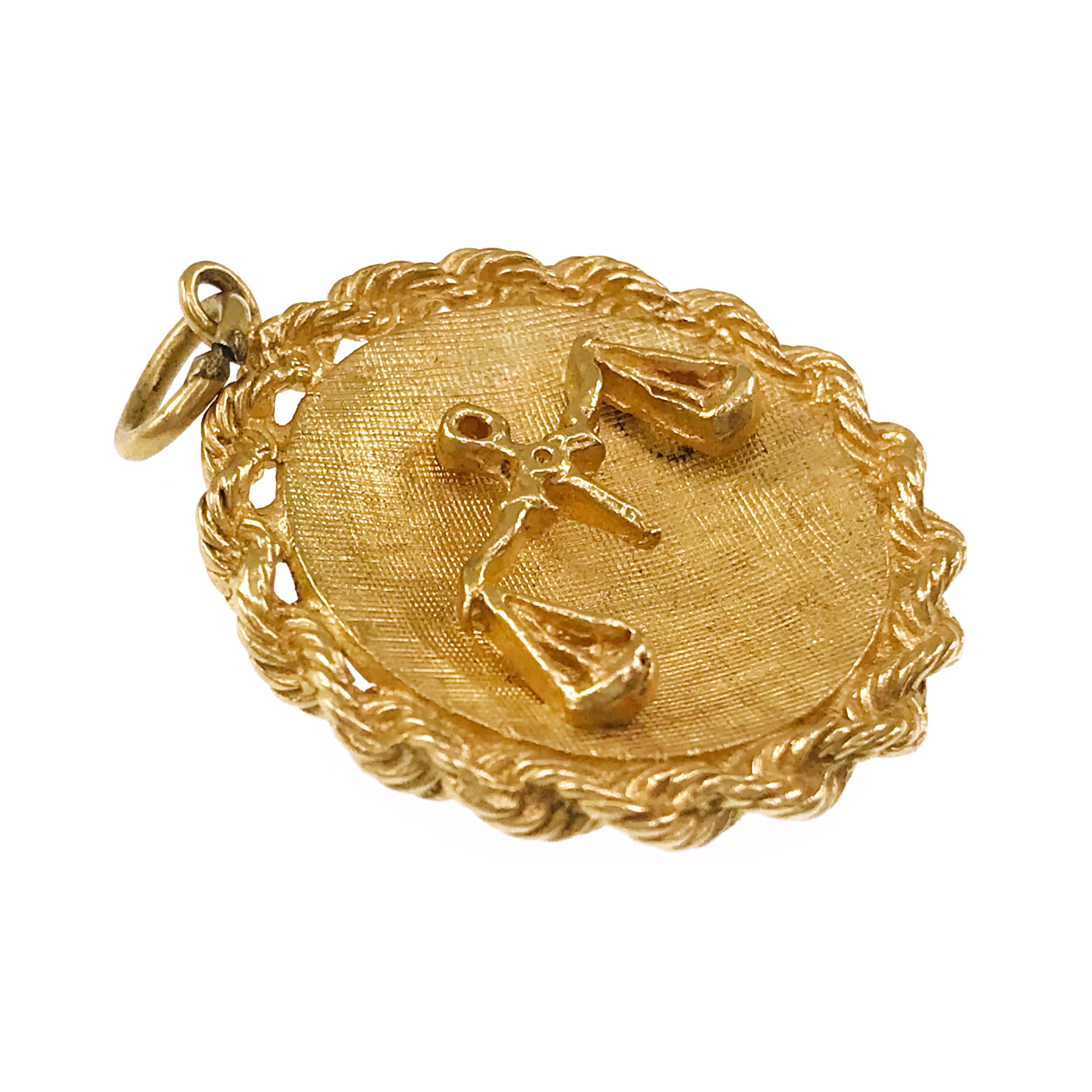 14 Karat Scales of Justice Pendant. Gold rope surrounds the entire outer edge of the pendant. The pendant measures 27.28mm x 3.63mm width. The front and back of the center have a florentine texture with the scales of justice in the center. The total