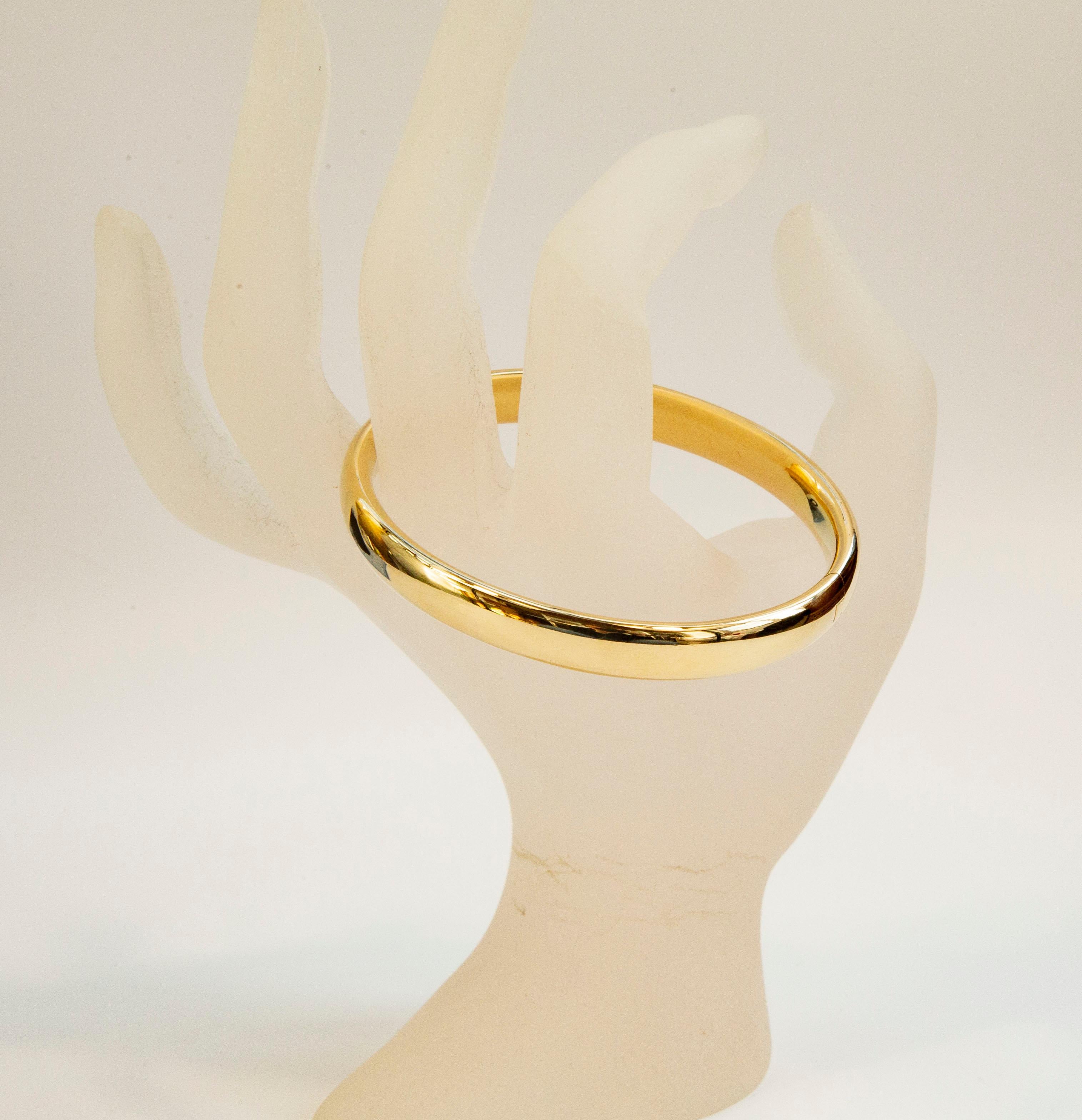 A vintage bangle, rigid bracelet made of 14 karat solid yellow gold. The bracelet features a hinge in the middle and a box clasp. 
The style of the bracelet is classic and minimalist. It would be a great addition of any type of outfit for a woman of