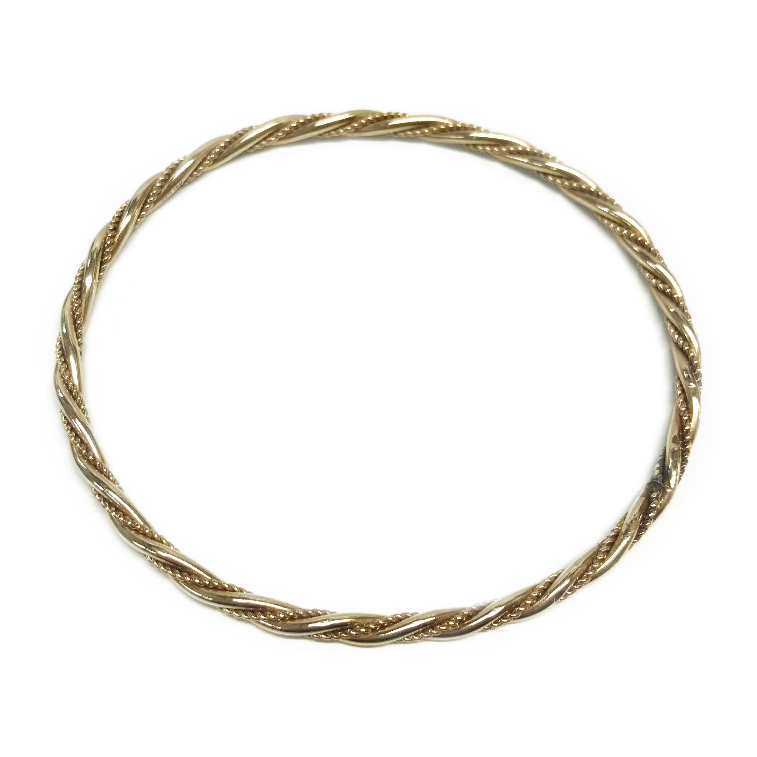 Bracelet torsadé semi-ovale en or jaune 14 carats. Le bracelet se compose de deux tubes tordus ensemble, l'un à finition lisse, l'autre à texture de corde. Le bracelet mesure 2 7/8
