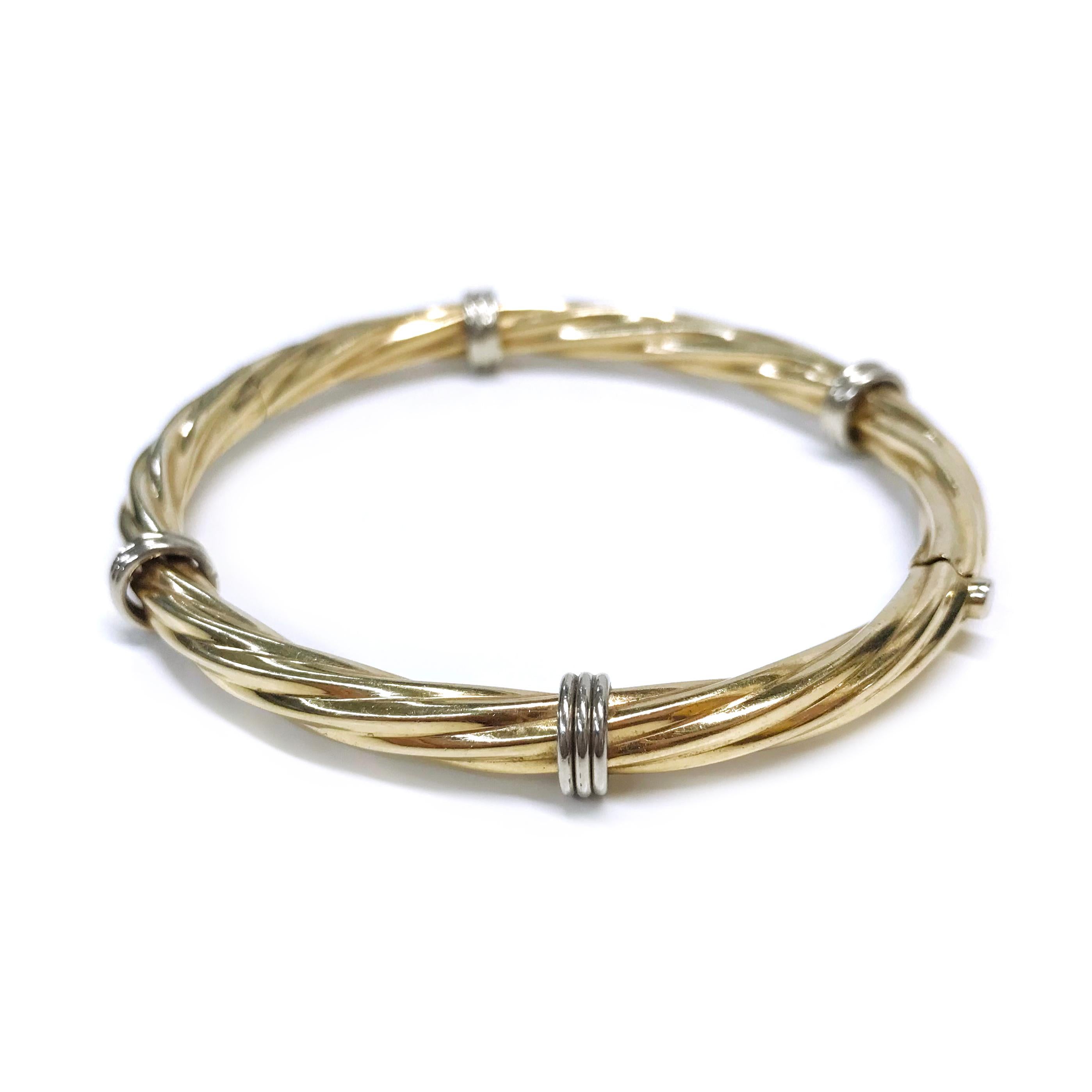 14 Karat two-toned Hinged Cable Bangle Bracelet. A classic yellow gold cable bangle with four white gold circular gold bars. The bangle measures 2.5mm wide and has a circumference of 7 3/4
