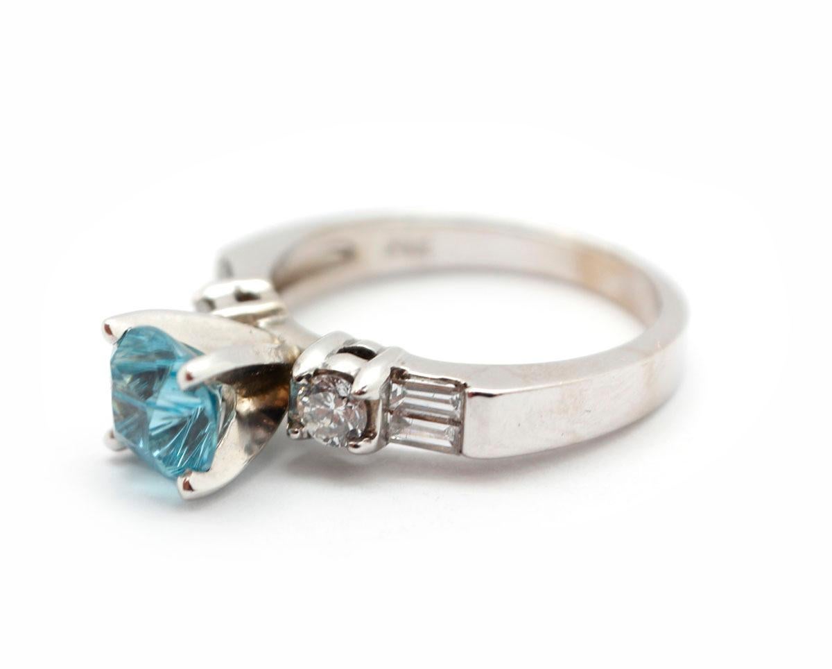 This fun cocktail ring is made in 14k white gold. It features a prong-set round blue zircon weighing 1.83 carats. The zircon is accented by two round diamonds and four baguette diamonds. The diamonds have a total weight of 0.43ct. The ring measures
