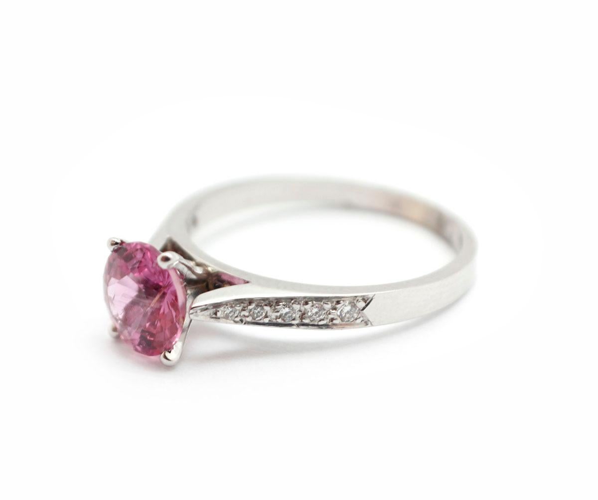 This vibrant ring features a 1.42-carat heated pink Madagascar sapphire at the center of a 14k white gold ring. The sapphire is accented by round diamonds for an additional weight of 0.08ct. The ring measures 7mm wide, and it weighs 2.6 grams. It is
