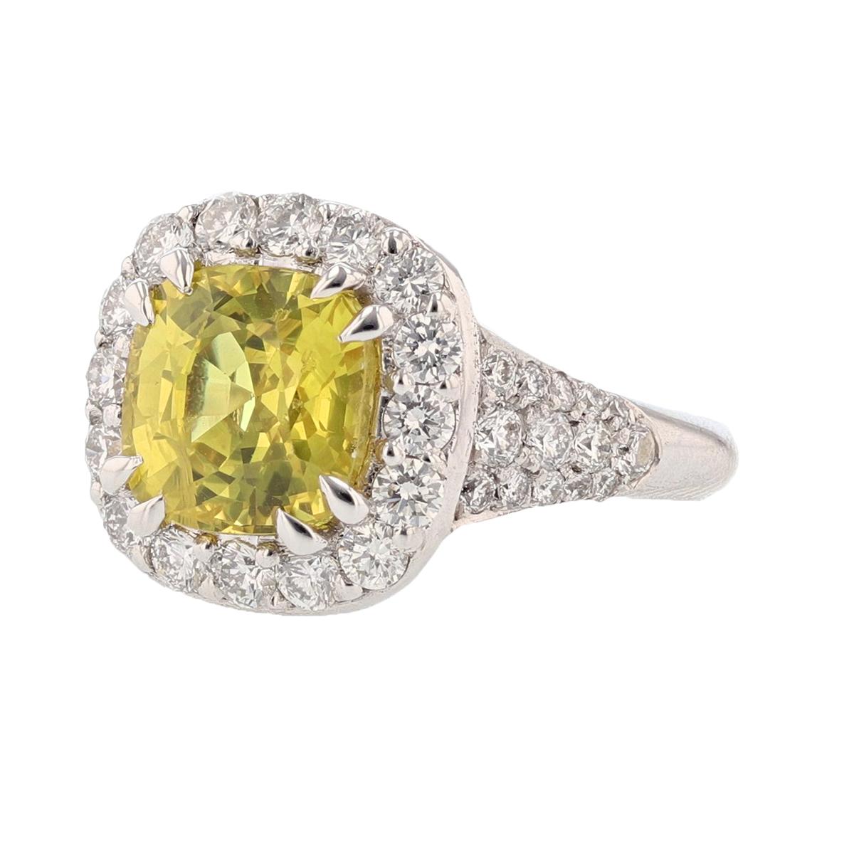 This ring is set in 14 karat white gold. The center stone is a Cushion cut Yellow Sapphire weighing 4.85 carats and is prong set. The Sapphire is AGL Certified (AGL-GB51157). The mounting features 44 round cut diamonds weighing 1.33cts.