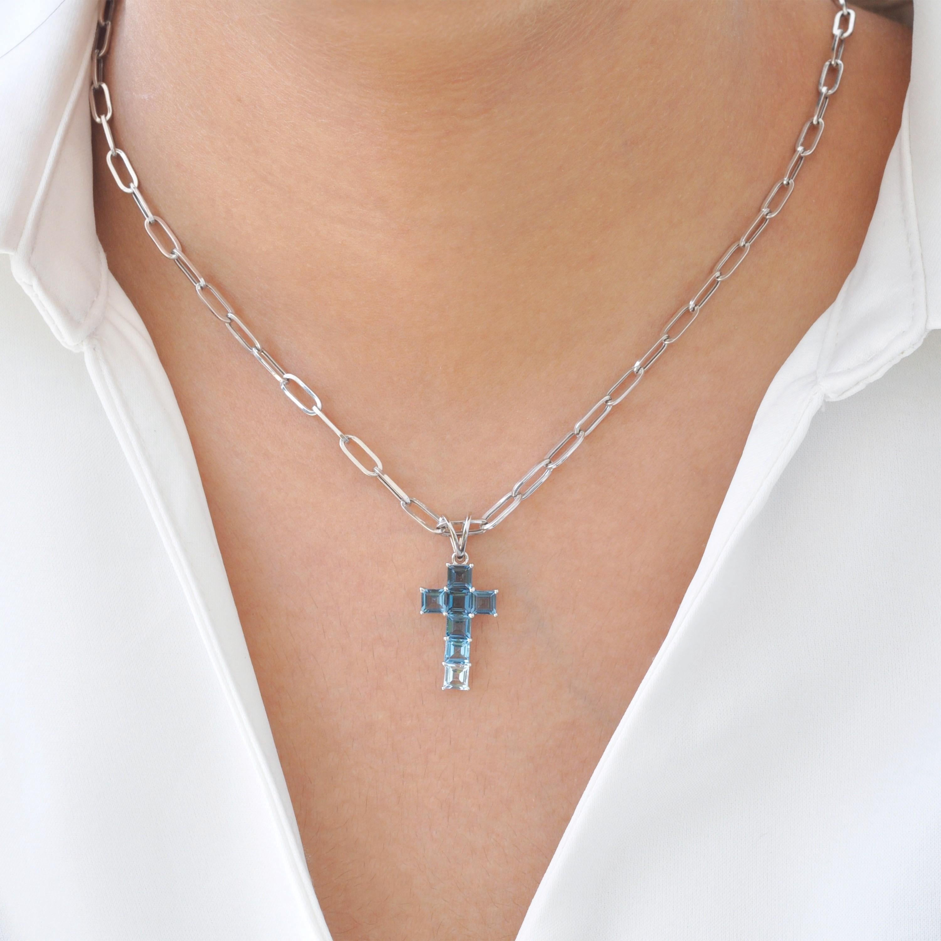 Ce pendentif croix en or blanc 14 carats avec topaze bleue est une étonnante représentation de la foi et de l'Elegance, conçu pour ceux qui apprécient à la fois la spiritualité et l'artisanat raffiné. Composé de sept pierres précieuses topazes
