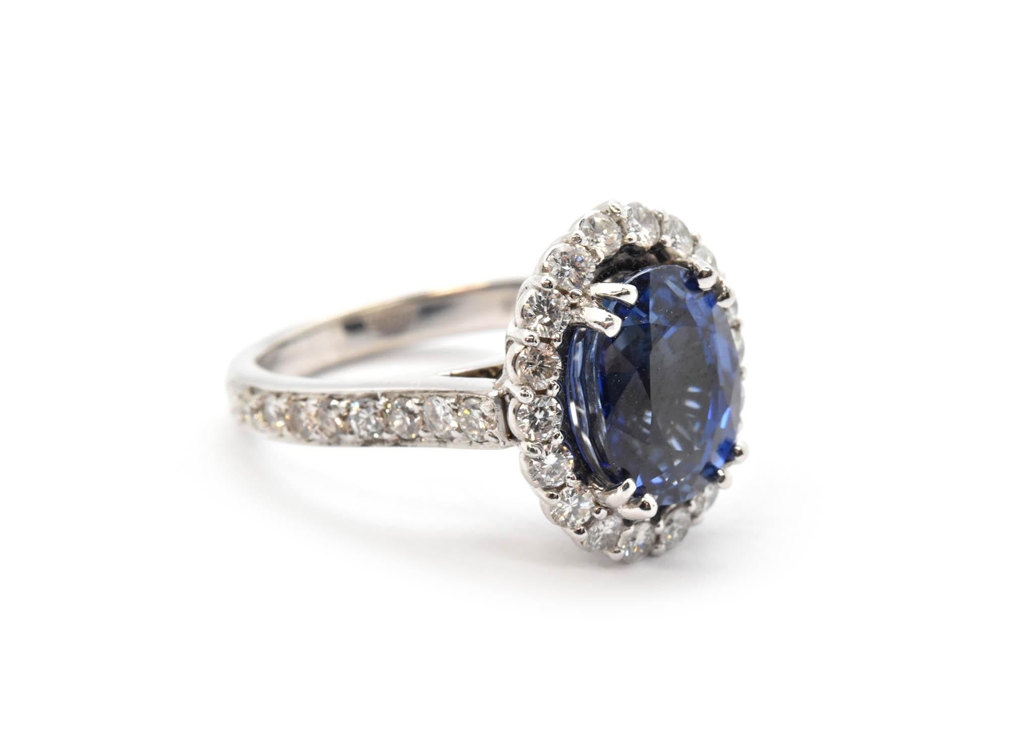 This classically beautiful ring features a faceted, oval-cut blue sapphire set into 14k white gold. The sapphire is surrounded by a halo of round brilliant diamonds for additional shine and sparkle. The sapphire weighs 5.31 carats, and the diamonds