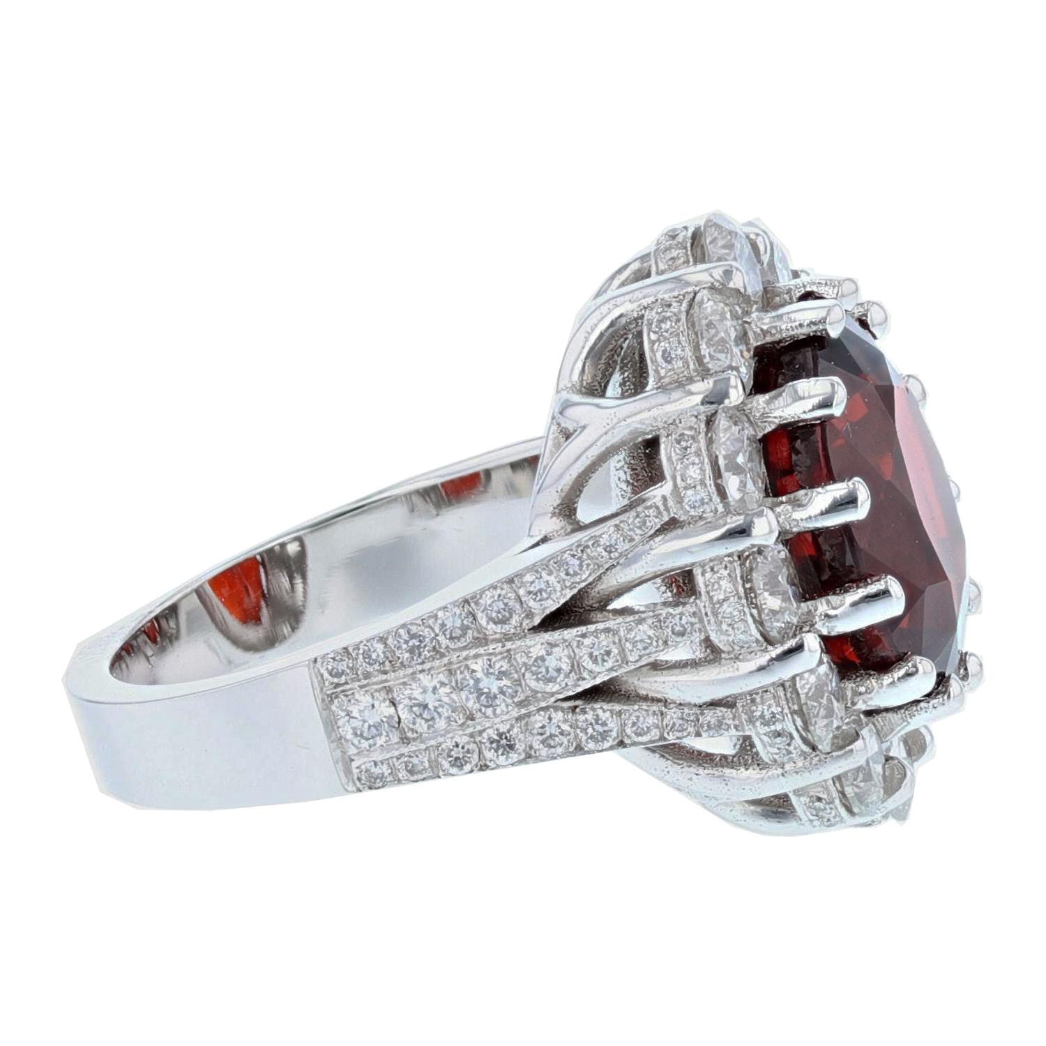 This ring is made in 14 karat white gold. The center stone is an Oval Cut Natural Spessartite Garnet weighing 8.93 carats and is prong set. The Garnet is AGL Certified, certificate number AGL-GB-51173. The mounting features 98 round cut diamonds