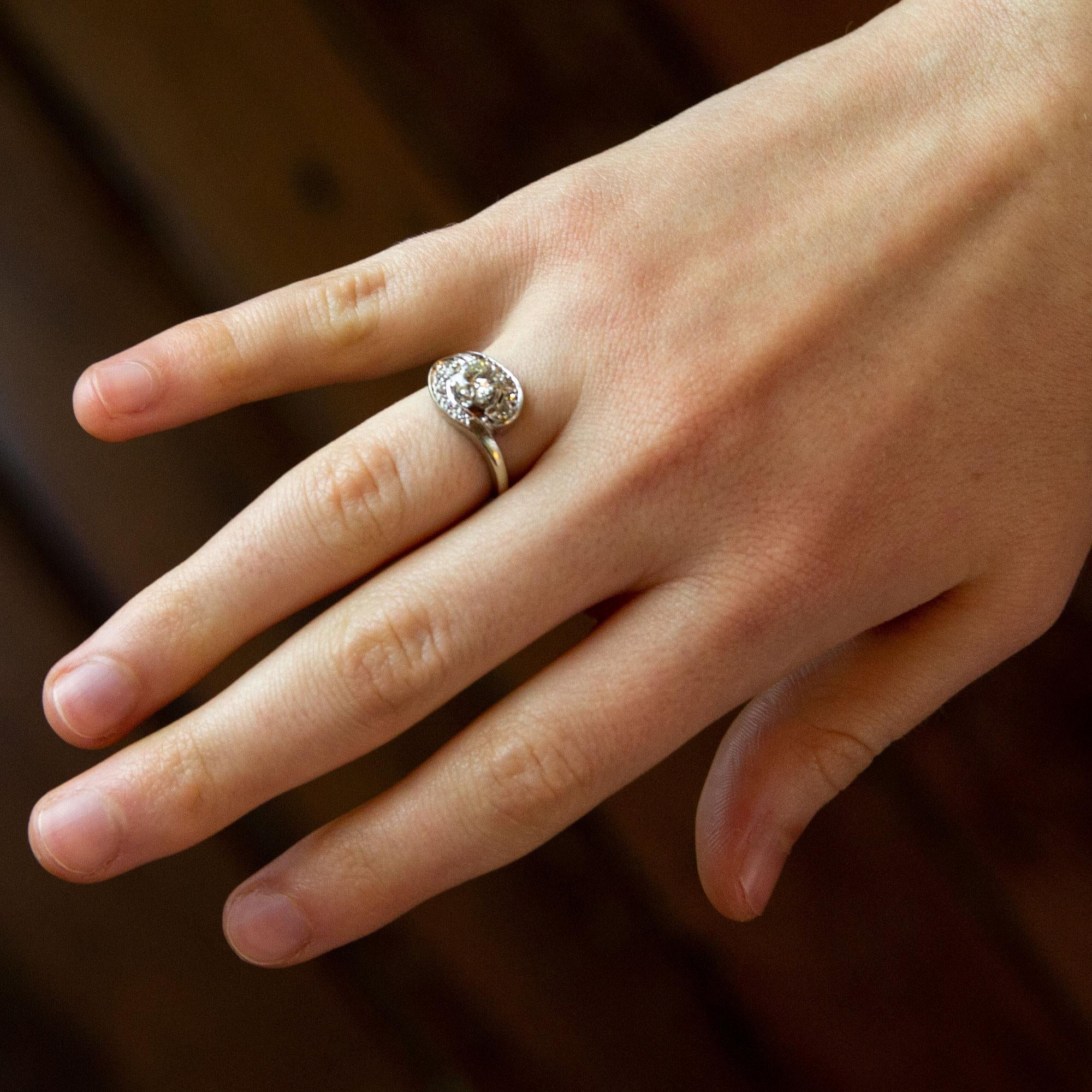 A fine and elegant white gold ring set with diamonds in a swirl design. The central stone is a brilliant cut diamond weighing 0.73 carat, of H/I colour and P1 clarity. The shoulders of this piece are each set with five single cut diamonds which