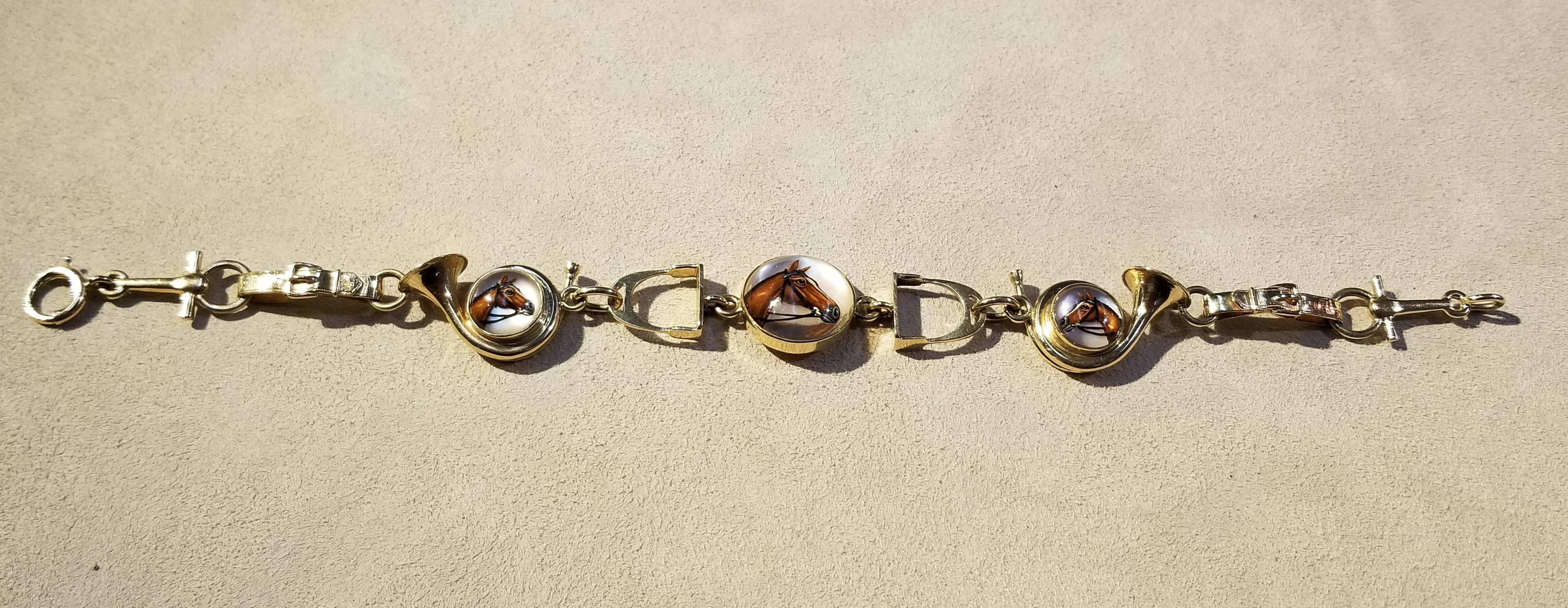 14 karat white gold equestrian bracelet with Essex crystal. Links are modeled after stirrups, bugles, and cinches. Three crystal medallions highlight portraits of horses. The bracelet features a spring ring clasp. Superb quality. Gold assey not