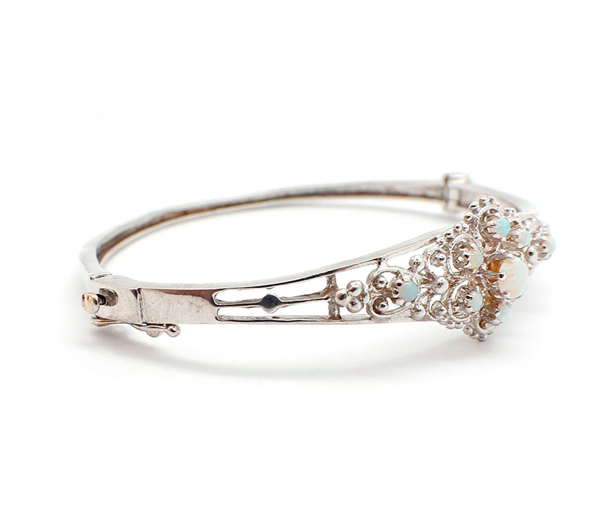 This beautiful bracelet is crafted in solid 14k white gold, and it features opals set decoratively across the face. The bracelet measures 16mm wide, and it weighs 13.22 grams. It will fit up to a 6.5-inch wrist.

