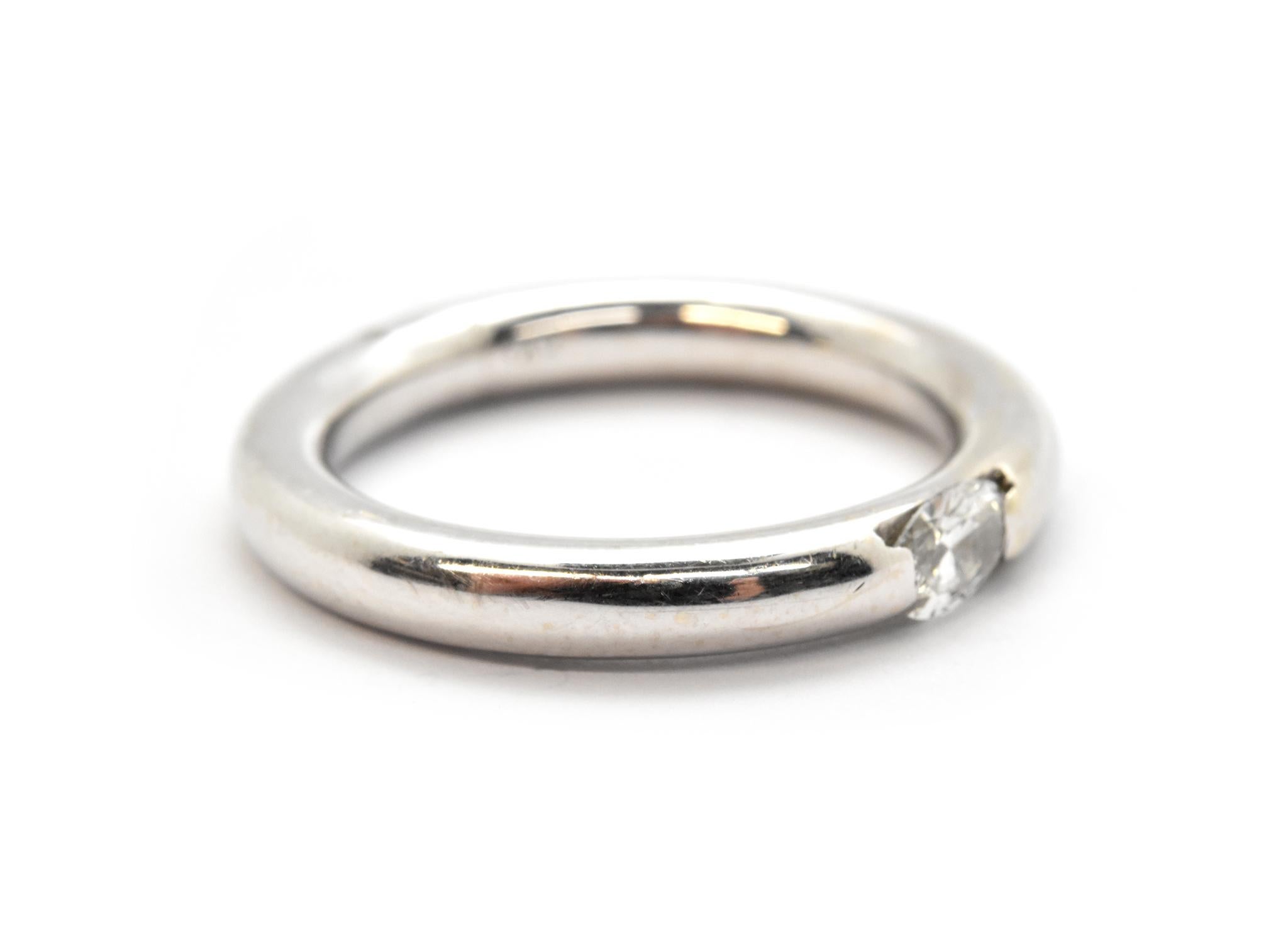 This contemporary ring is made in solid 14k white gold. It features a tension-set oval-cut diamond weighing approximately 0.25ct. The diamond is graded I in color and SI in clarity. The band measures 3mm wide, and it weighs 6.28 grams. The ring is a