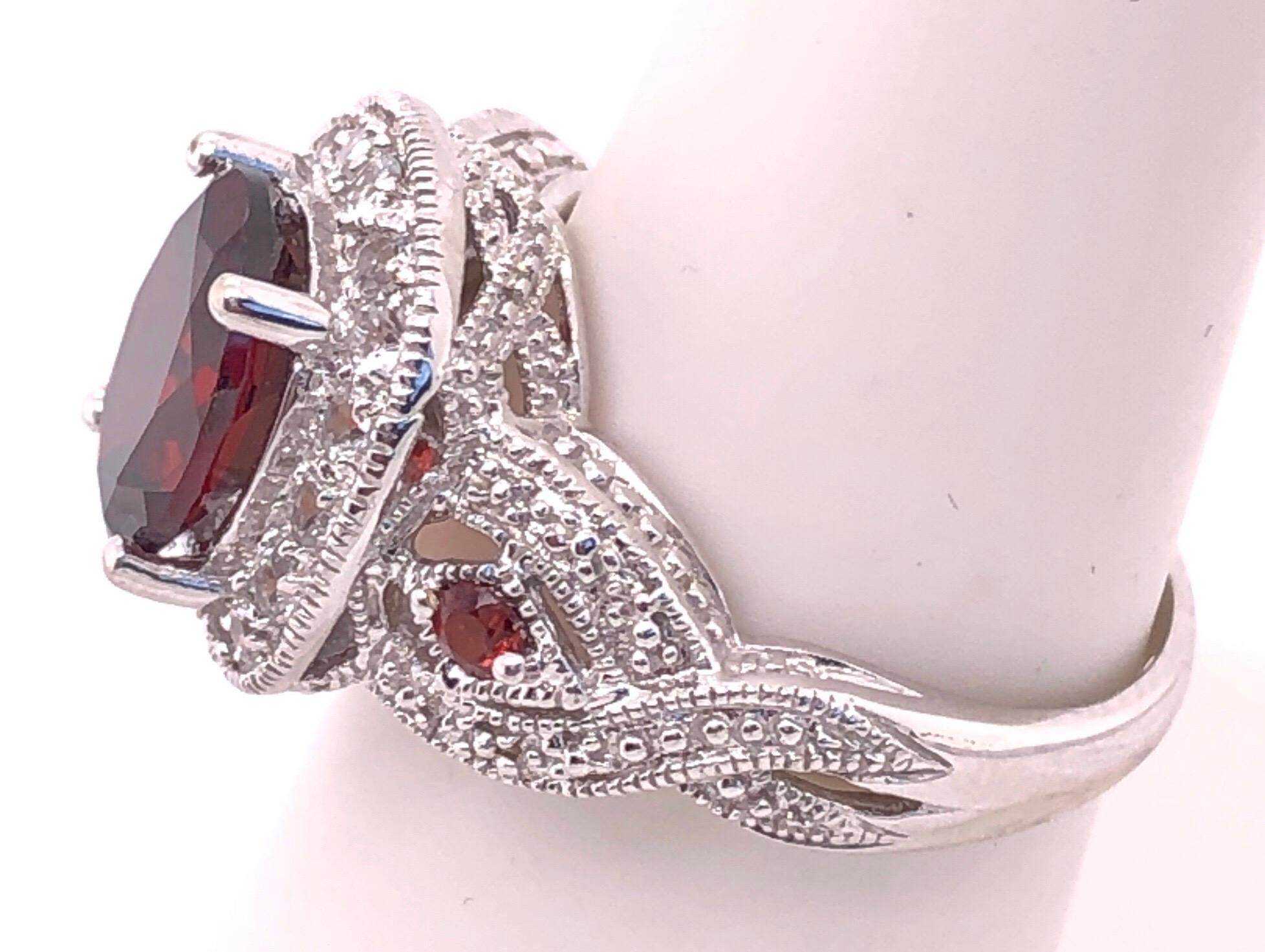 14 Karat White Gold Antique Ring Oval Garnet Center With  Accents Size 7. The garnet may be synthetic. 
16 piece round cubic zirconia
5 grams total weight.
