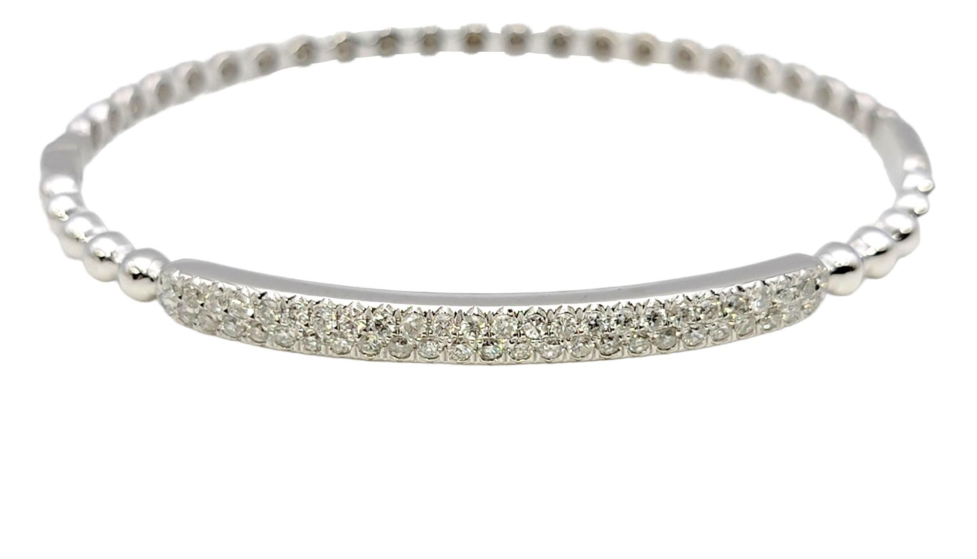 Contemporary bangle bracelet in a 14K white gold featuring a narrow bubble design. The top portion of the sleek bracelet is adorned with two elegant row of sparkling pave diamonds. Stack it with other bracelets for a modern look, or simply wear on
