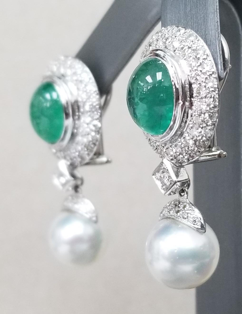 14k white gold cabochon cut emeralds weighing 9.55cts. surrounded by 2 rows of paved round full cut diamonds of very fine quality weighing 2.02cts. with a dangling 11mm south sea pearl of fine quality.  It has a lever back and post for support.