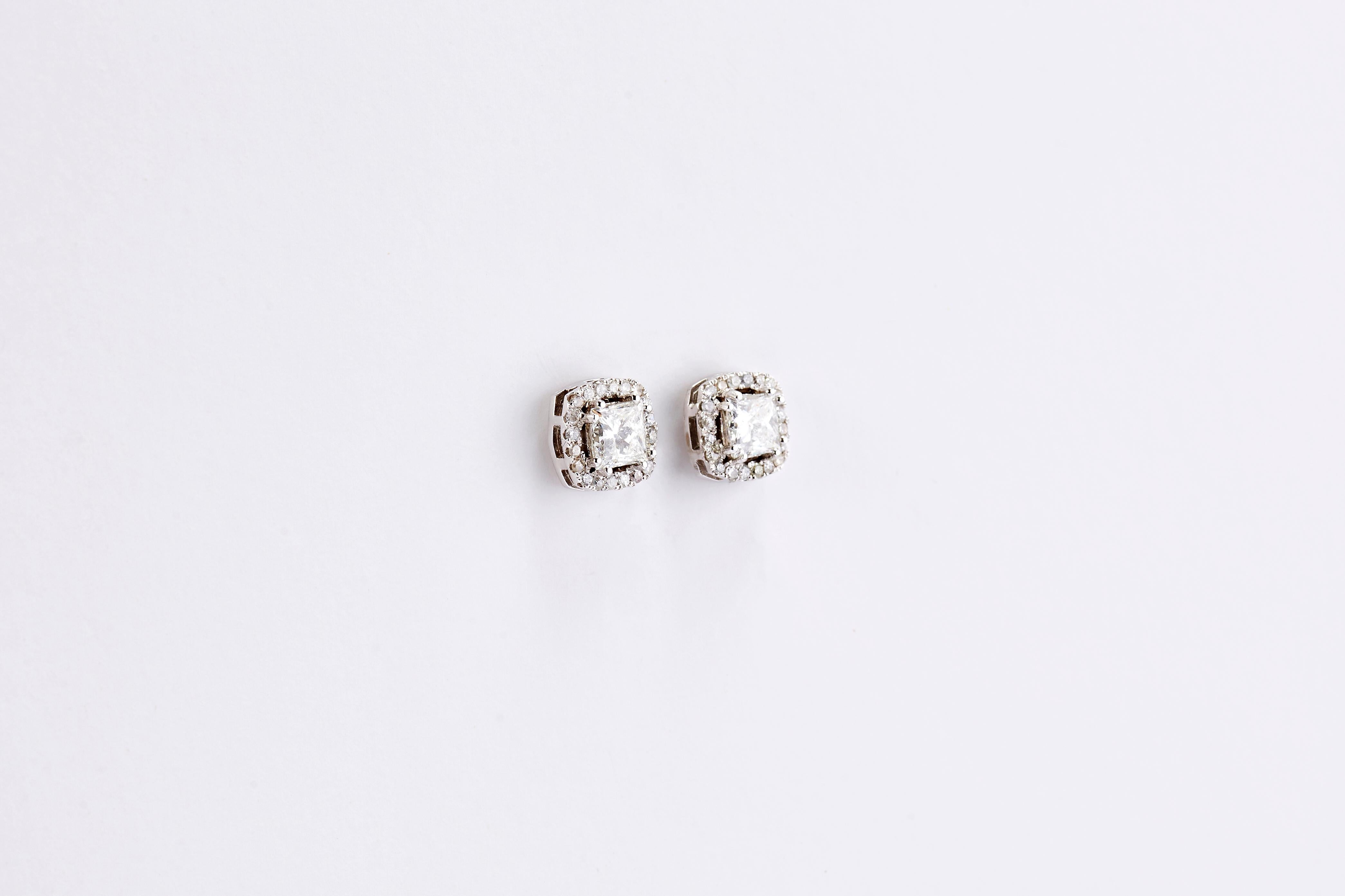 14 Karat White Gold Princess Cut Diamond Earrings with a Halo 

White gold 14K gorgeous diamond earrings classic design with a diamond halo. 
Princess cut center diamonds 1.01 and 1.02 carat, F VS1. Side stones 0.80 ct.
Total weight 3.90 grams.