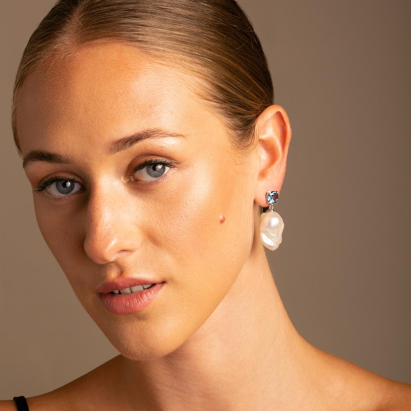 A Striking Cushion Cut London Blue Topaz combined with a luminous natural white baroque pearl drop to create a romantic show stopping earring.

Set in a high polish 14k White gold basket with claw setting to elevate the look.

London Blue Topaz 8mm