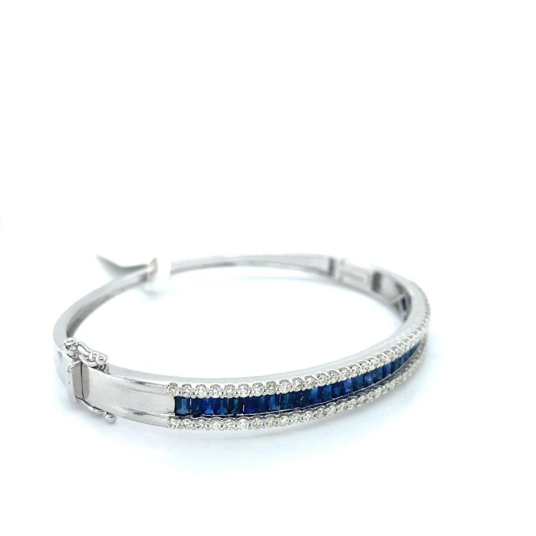 This stunning bangle bracelet is made with 14 karat white gold. The center row has 3.24 cttw of baguette sapphires with two outer rows of diamonds equaling 1.32cttw. This bracelet has a double safety catch and can fit a 6.5 inch wrist. The bangle is