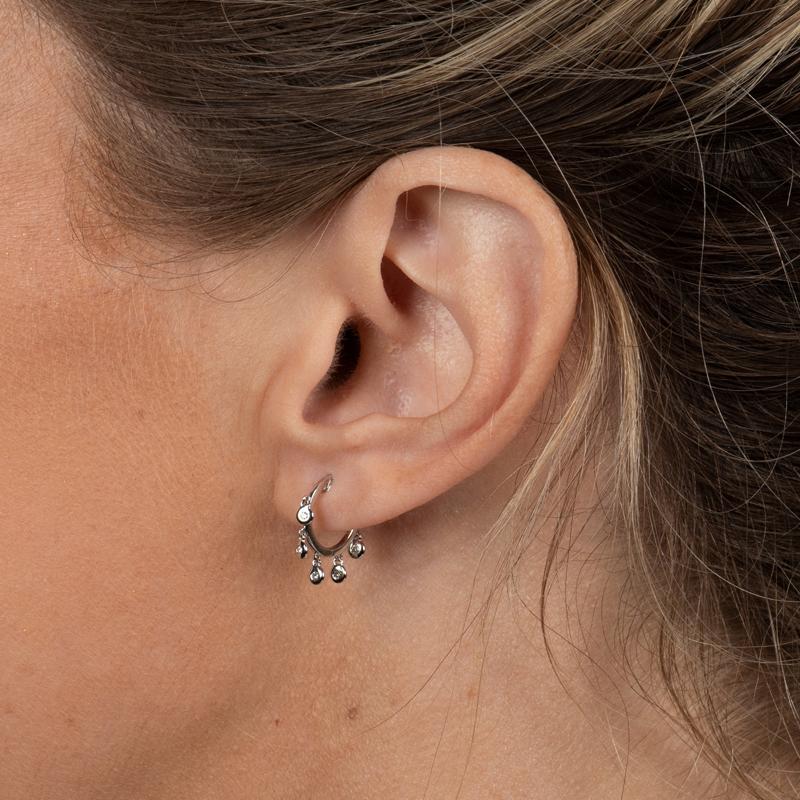 These 14 karat white gold huggie hoop earrings feature 5 dangling diamonds. 
Measurements: Diameter approximately 11.60mm