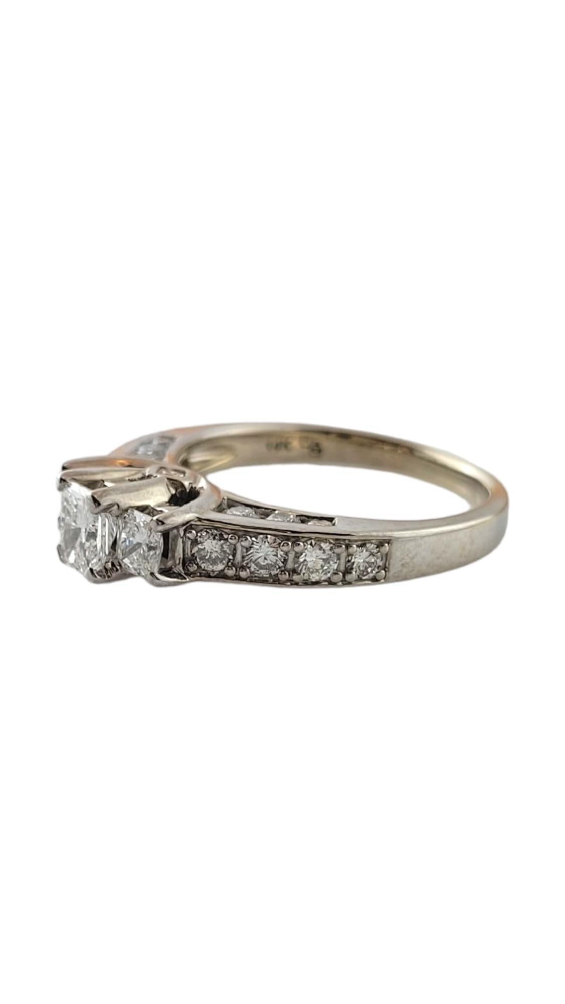 Dieser funkelnde Ring besteht aus drei Diamanten im Prinzessinnenschliff (Mitte: 0,30 ct., Seiten: 0,15 ct.), sechs runden Diamanten im Brillantschliff und acht Baguette-Diamanten, die in klassischem 14-karätigem Weißgold gefasst sind.  

Schaft:  3