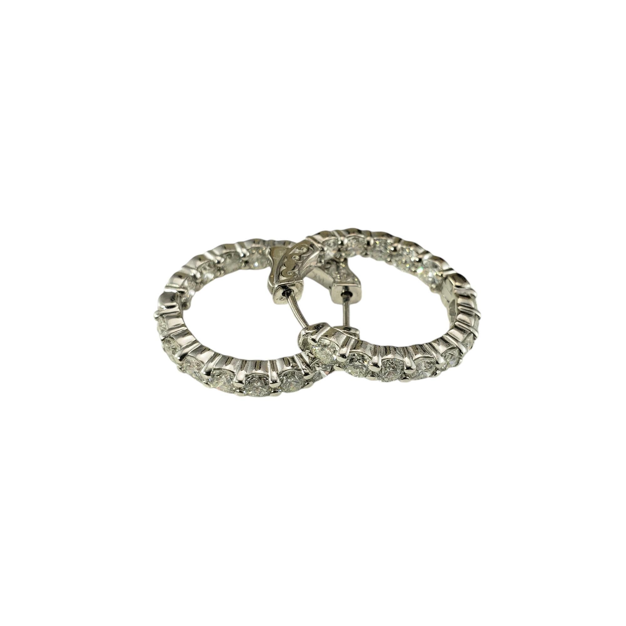 Questi scintillanti orecchini a cerchio con cerniera presentano ciascuno 13 diamanti rotondi taglio brillante incastonati in oro bianco 14K. 

Larghezza: 3.5 mm.

Peso totale approssimativo dei diamanti: 3,00 - 3,38 ct.

Colore del diamante: