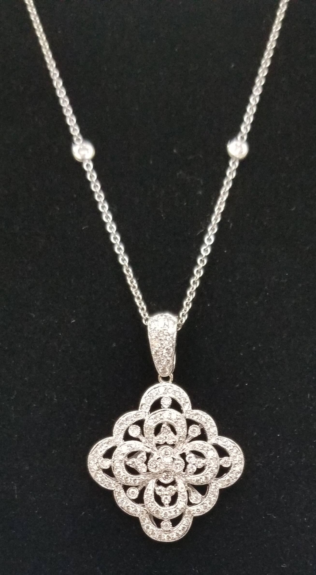 14k white gold diamond pendant, containing 125 round full cut diamonds of very fine quality weighing 1.50cts. set in a filigree setting on a 16 inch chain with 2 bezel set diamonds.