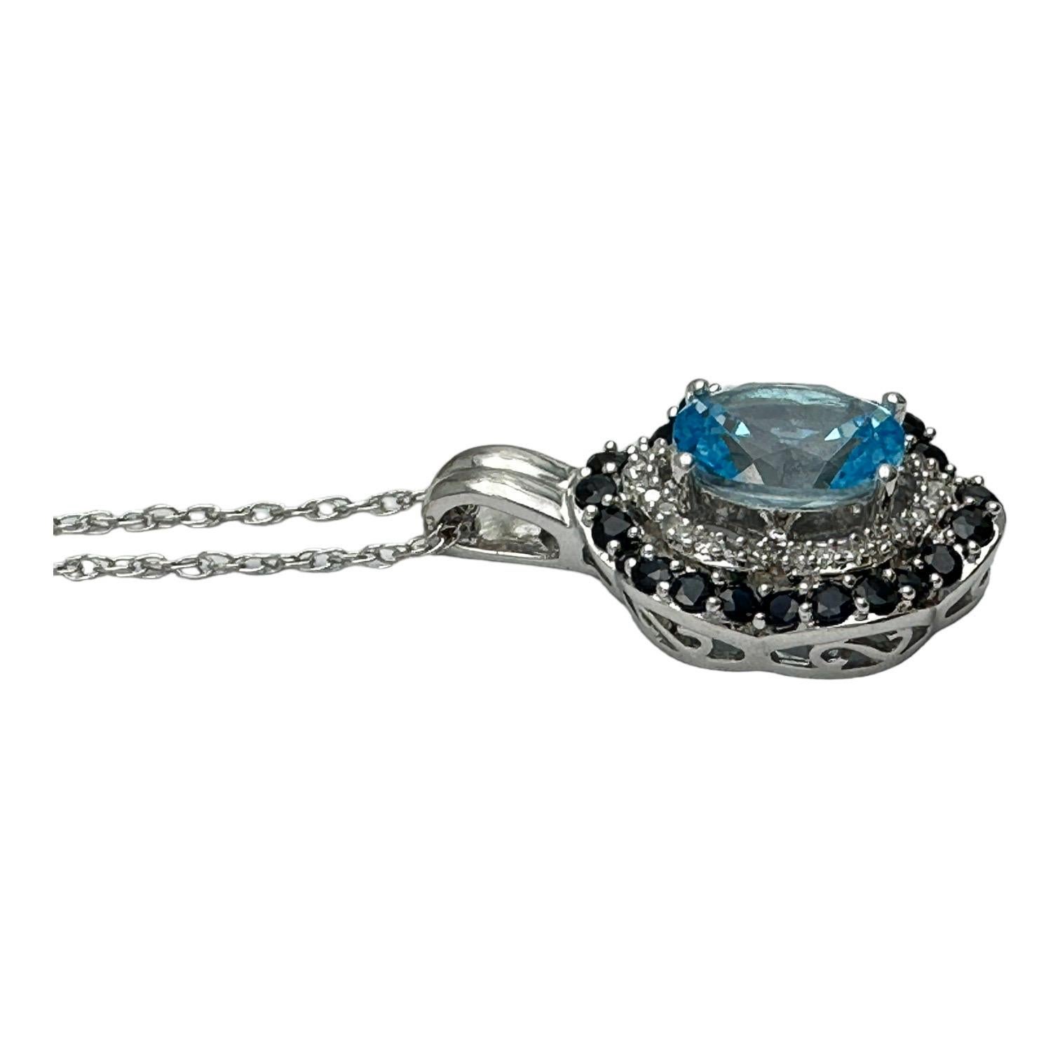 14 karat white gold pendant features an oval-shaped Swiss blue topaz gemstone surrounded by a row of genuine diamonds and an outer row of blue sapphires. The combined gemstone weight of this pendant is 2.00 carats.

Measures 15mm or 3/4 inches plus