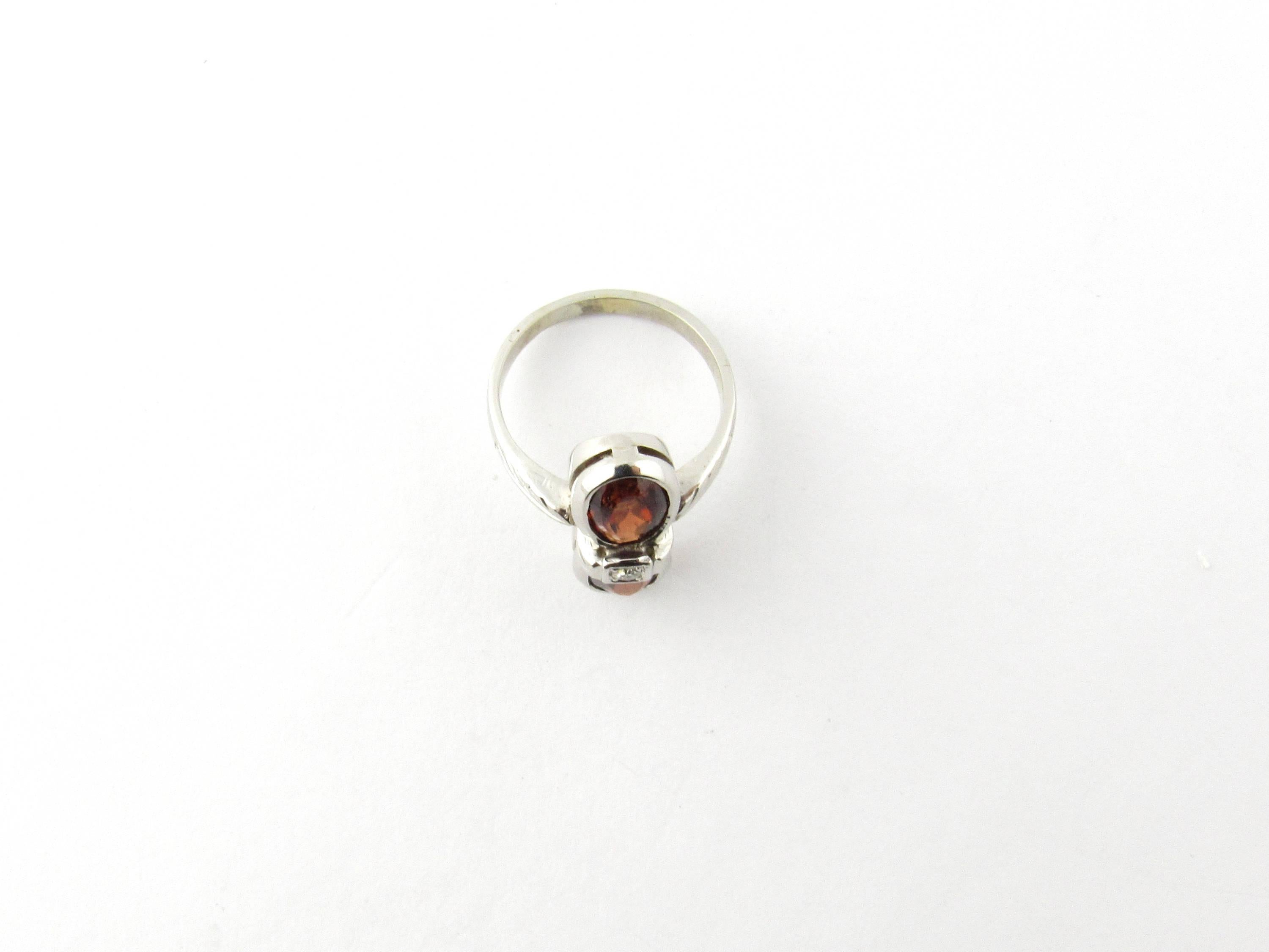 Vintage 14 Karat White Gold Garnet and Diamond Ring Size 5- 
This stunning ring features two oval garnet stones (7 mm x 6 mm each) accented with one sparkling single cut diamond and set in 14K white gold. Top of ring measures (18 mm x 7 mm). Shank 2