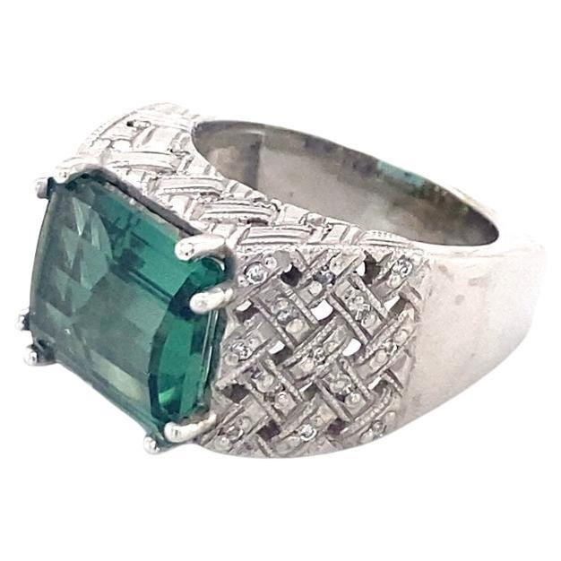 This gorgeous ring is made of 14 karat white gold. The ring features a 5.50ct emerald green tourmaline center stone and has 0.38cttw of diamonds in the band. This one of a kind piece is custom made by our expert jewelers. 