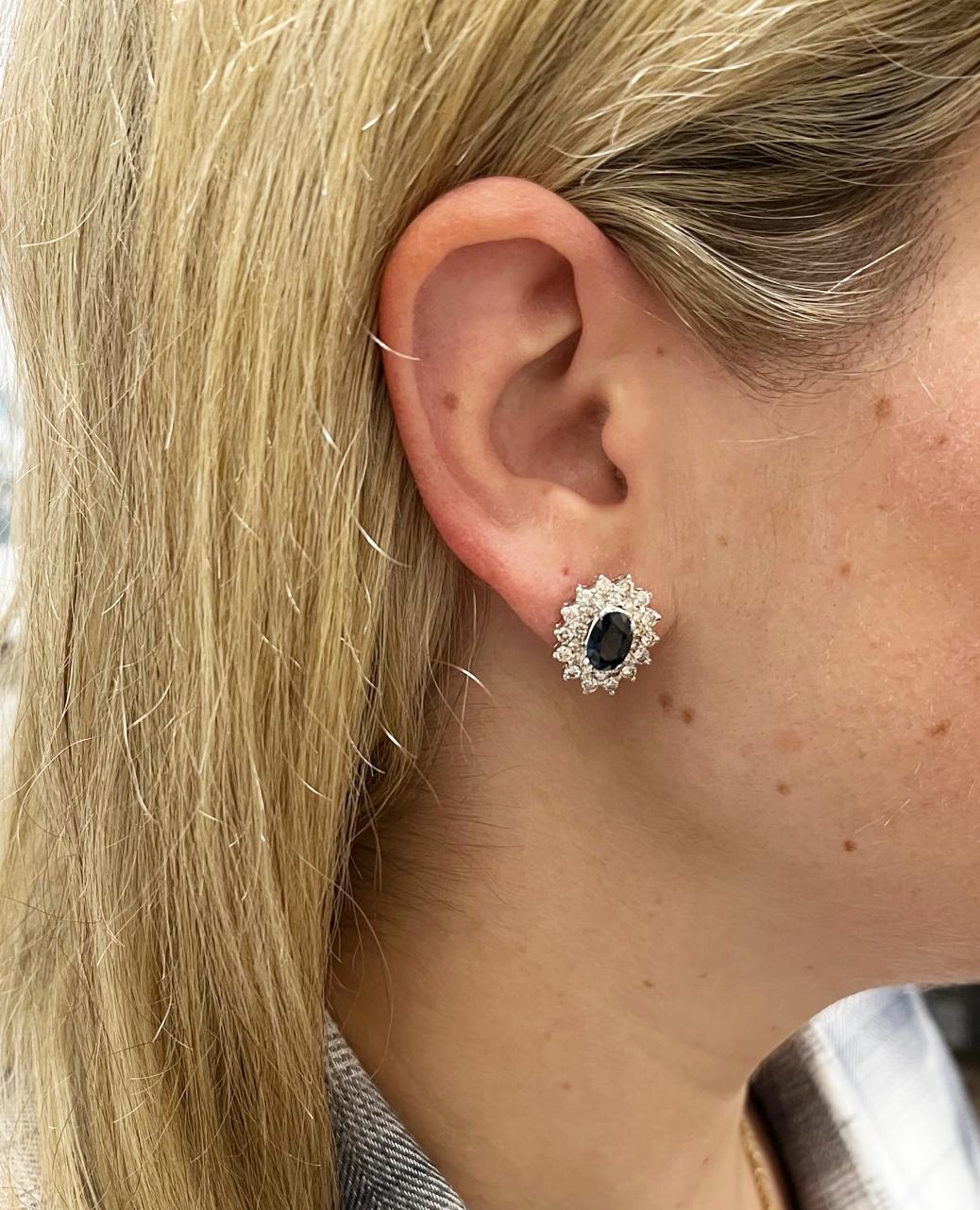 14 Karat White Gold Natural Diamond & Blue Sapphire Halo Cluster Earrings 
Metal: 14k white gold
Weight: 8.37 grams
Diamonds: Approx. 2.00 CTW I VS round natural diamonds
Sapphires: 2 oval blue sapphires, approx. 1.33 carats each 
Dimensions: 17 x