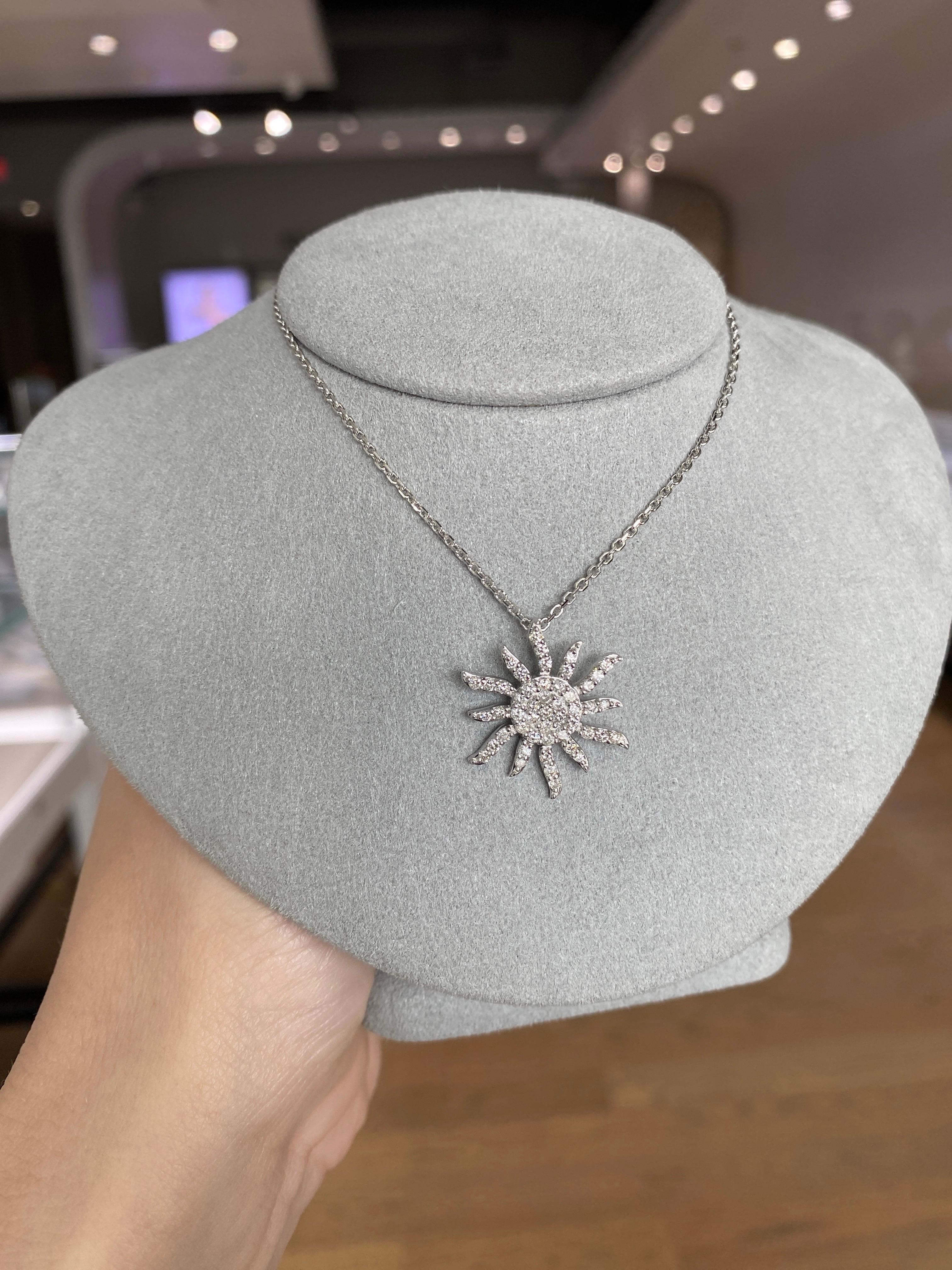 This elegant 14 karat white gold necklace features a captivating sun pendant adorned with 49 natural round brilliant diamonds totaling 0.64 carats. The polished finish enhances the brilliance of the diamonds, making this piece a perfect statement