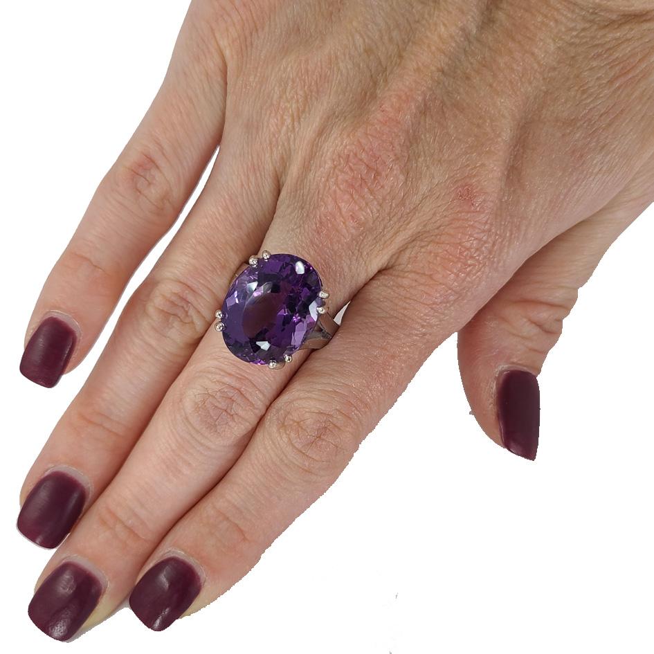 14 Karat White Gold Solitaire Cocktail Ring Featuring A Double-Prong Set 17.87 Carat Oval Amethyst On A Split Band. Current Finger Size 6; Purchase Includes One Sizing Service. Finished Weight is 11 Grams.