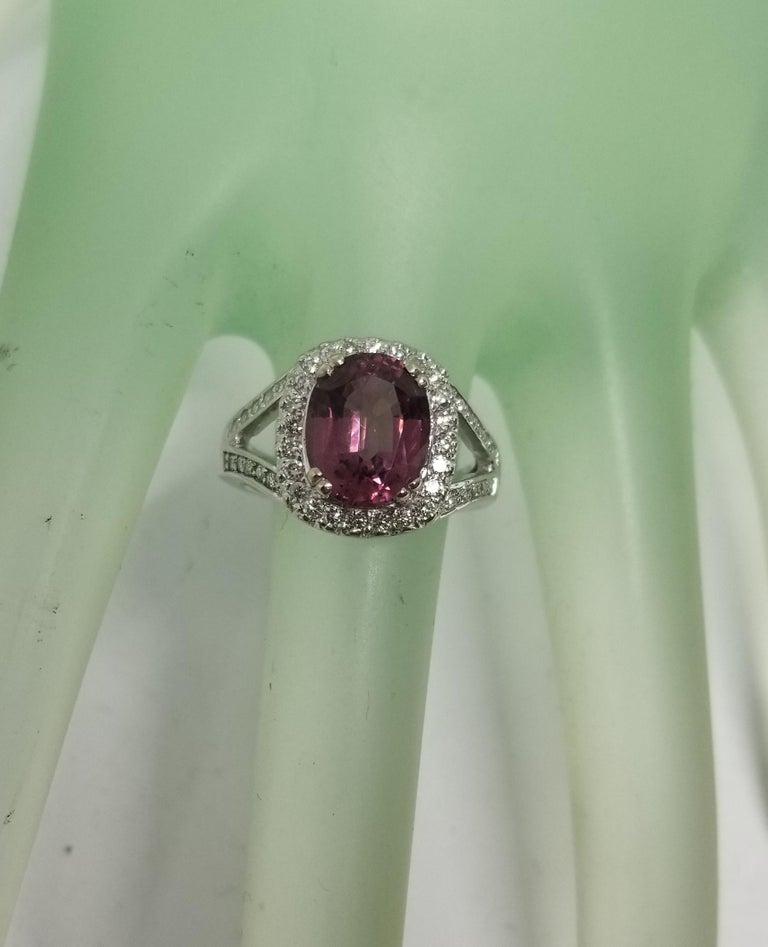 14 karat white gold Pink Tourmaline diamond halo ring, containing 1 oval pink tourmaline of gem quality weighing 2.75cts.  and 46 round full cut diamonds of very fine quality weighing .60pts.  This ring is a size 6 but we will size to fit for free.