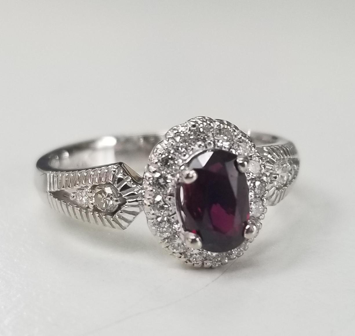 14 karat white gold oval Ruby and diamond halo ring, containing 1 oval ruby of gem quality weighing .83pts.  and 20 round full cut diamonds of very fine quality weighing .35pts.  This ring is a size 6.5 but we will size to fit for free.