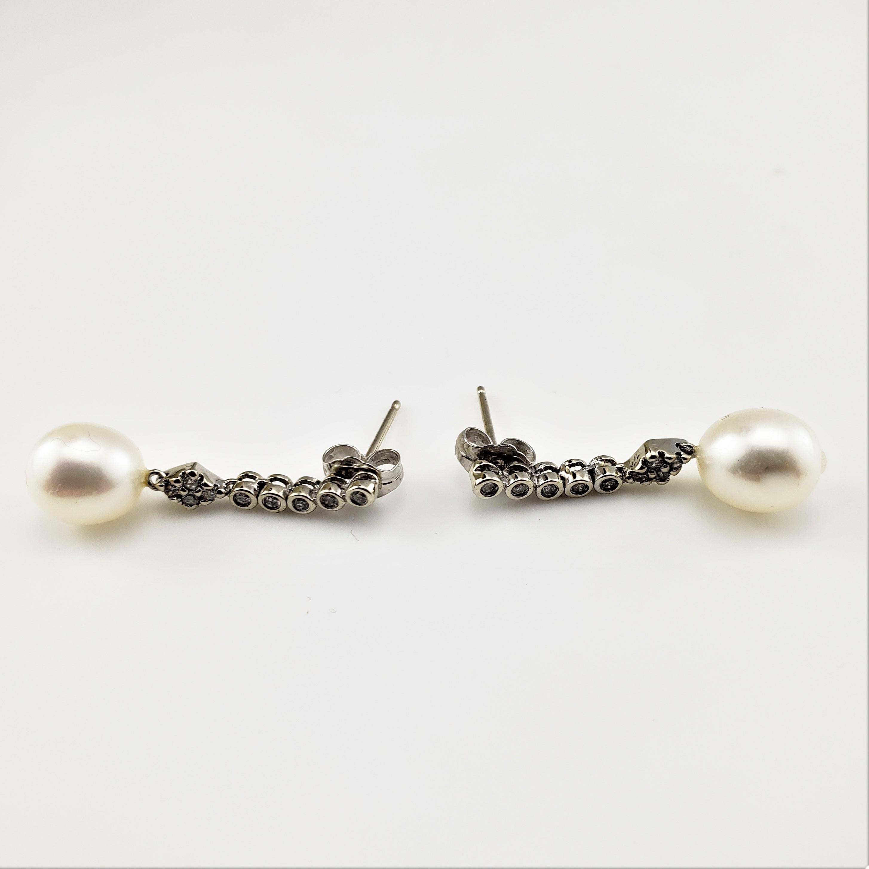 14 Karat White Gold Pearl and Diamond Dangle Earrings-

These dangling earrings each feature one 9 mm pearl and nine round brilliant cut diamonds set in classic 14K white gold.

Approximate total diamond weight:  .20 ct.

Diamond color:  I

Diamond
